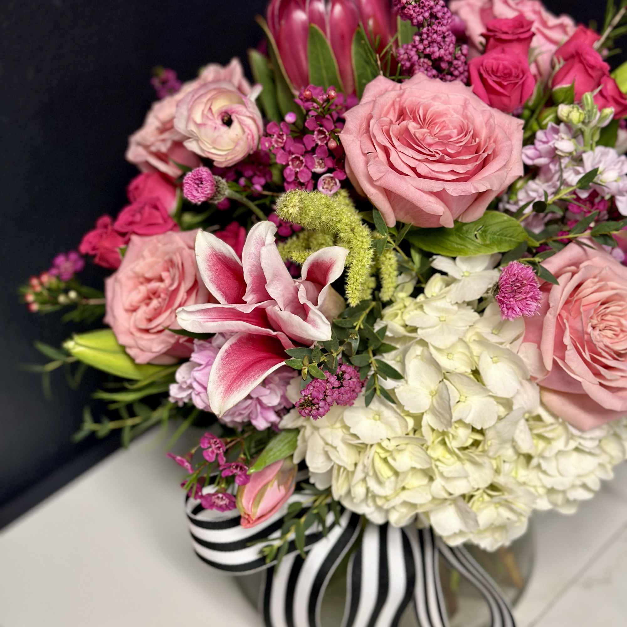 Pink roses and lilies arranged with white hydrangeas in a glass vase