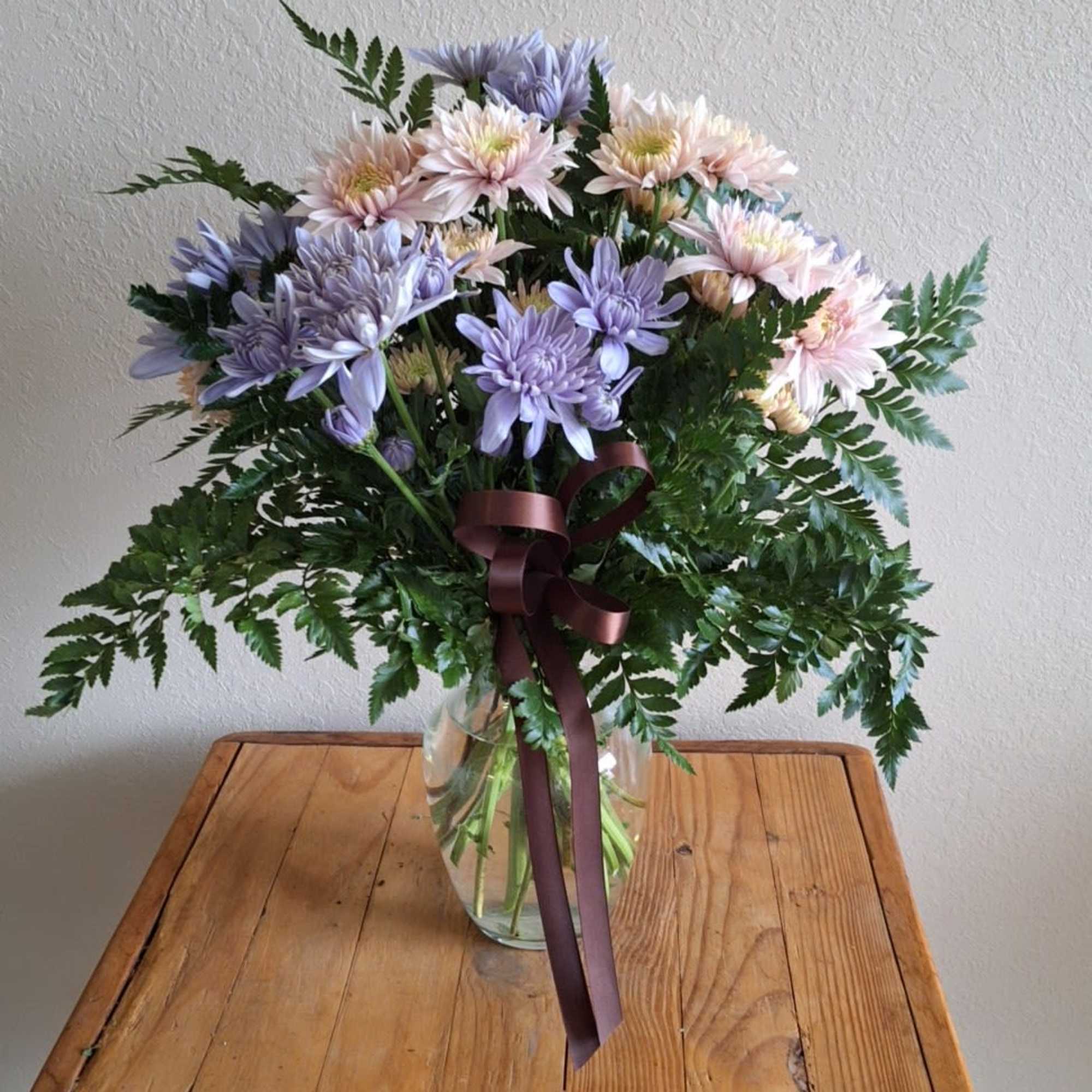 Bouquet of lavender and blush flowers in a glass vase with a ribbon