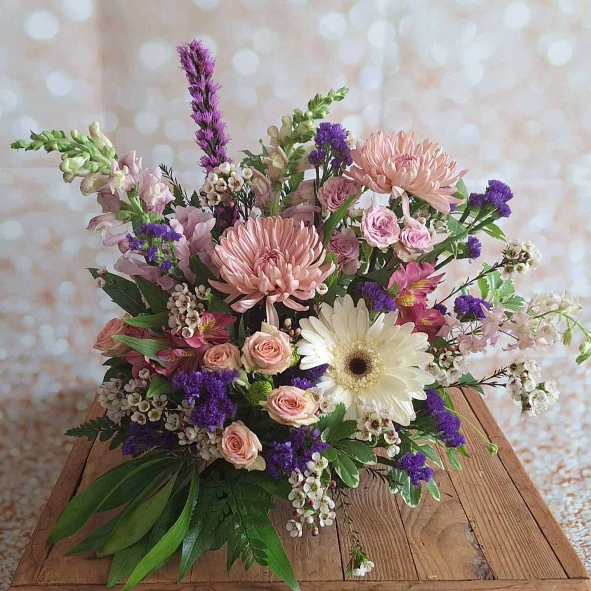 Mixed pink and purple bouquet with a white gerbera daisy on a wooden table