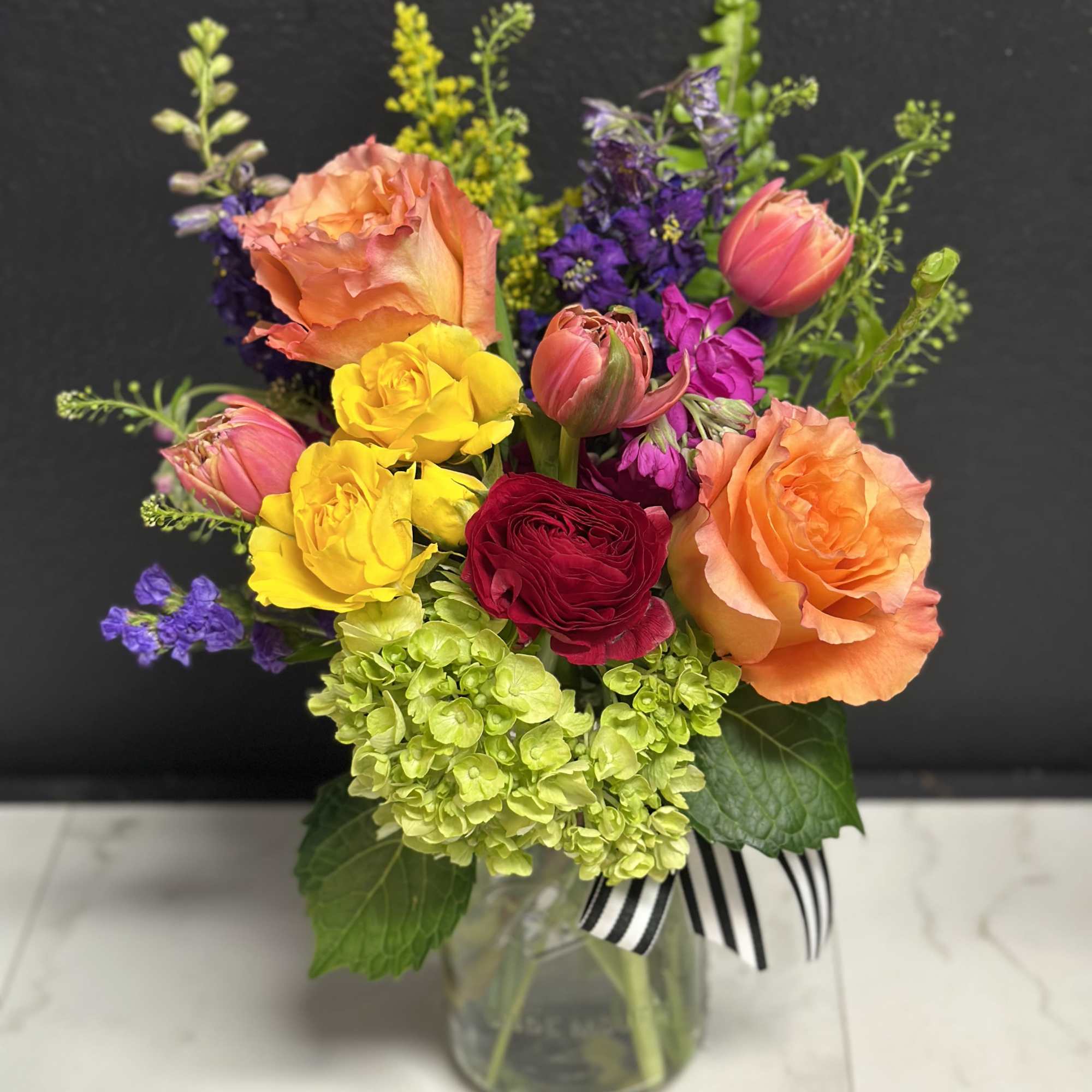 A bright, colorful, garden mix with season's prettiest blossoms. Arranged in our