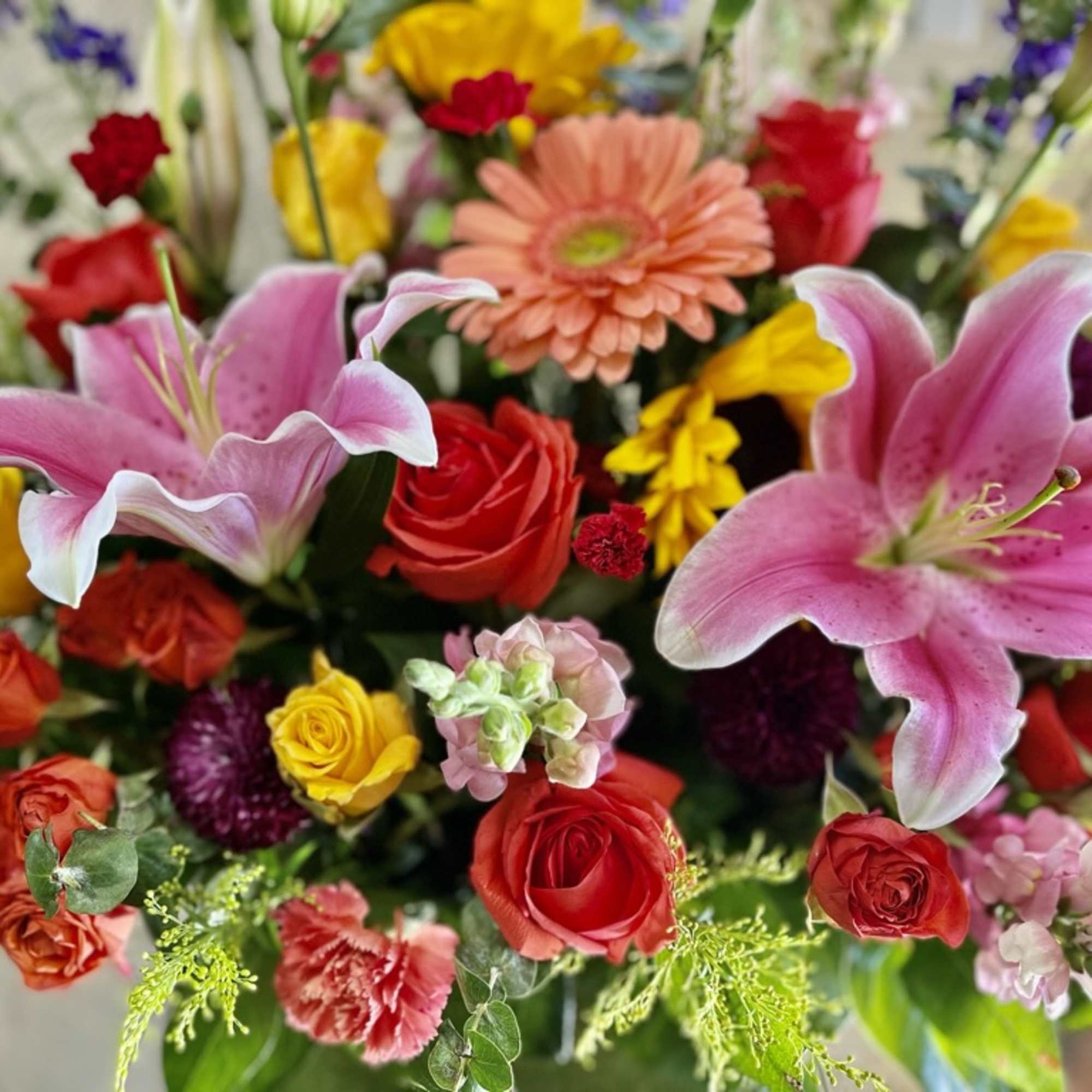 Mixed bouquet with pink lilies, red and yellow roses, and a peach gerbera daisy