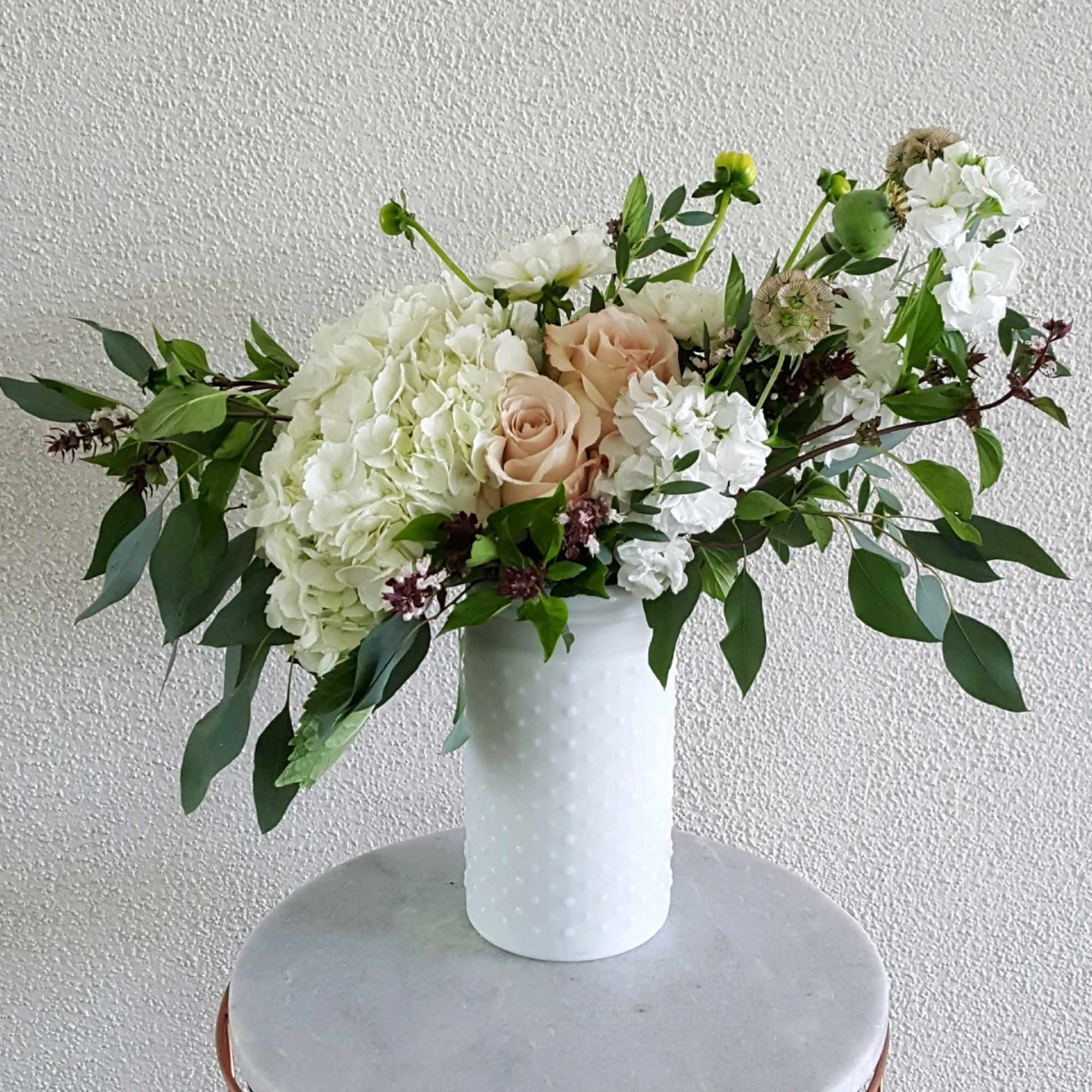 White and blush floral arrangement in a white vase