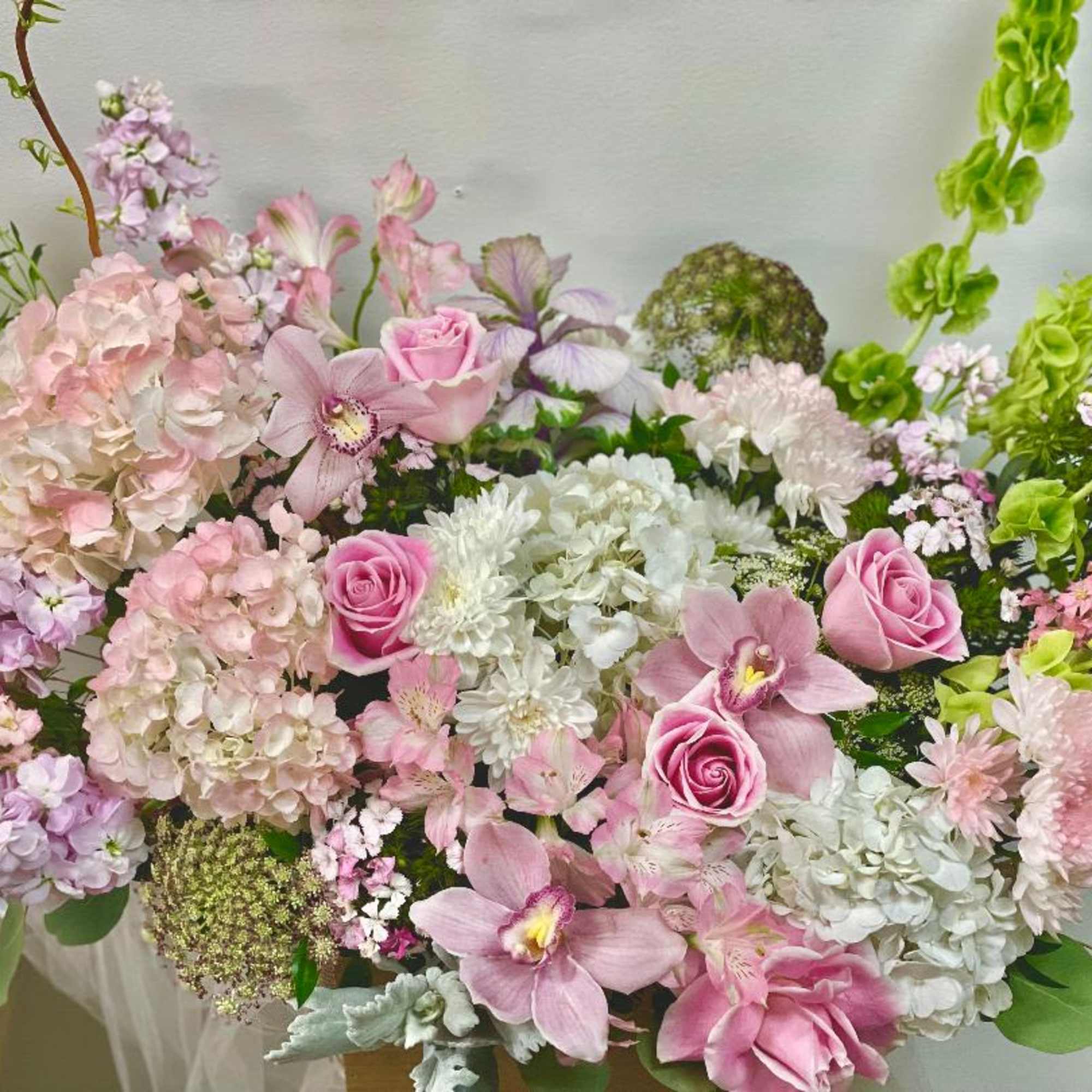 Pink and white floral arrangement with roses, orchids, and hydrangeas