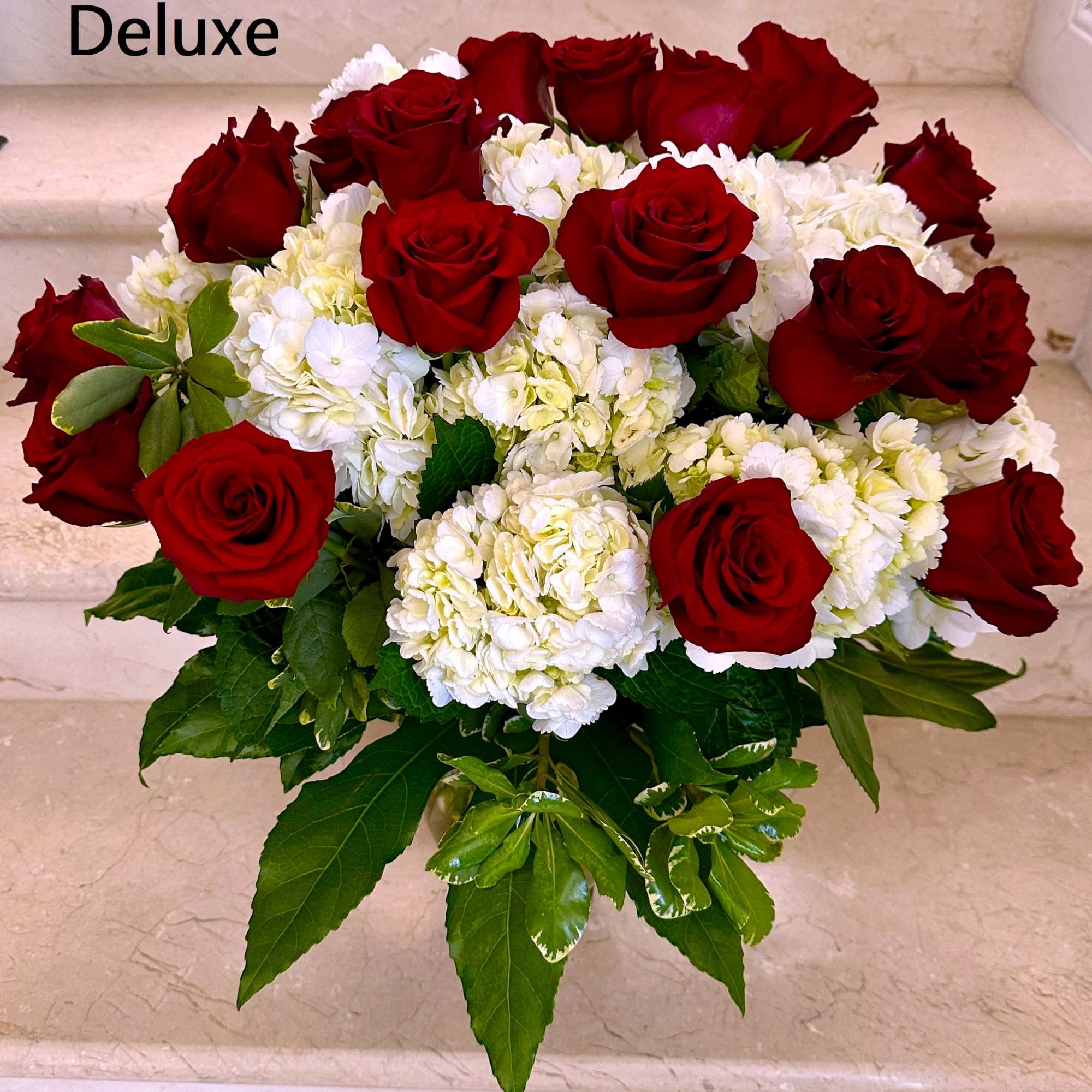 Standard: 12 Red Roses with White Hydrangeas arranged in a vase.
Deluxe: 