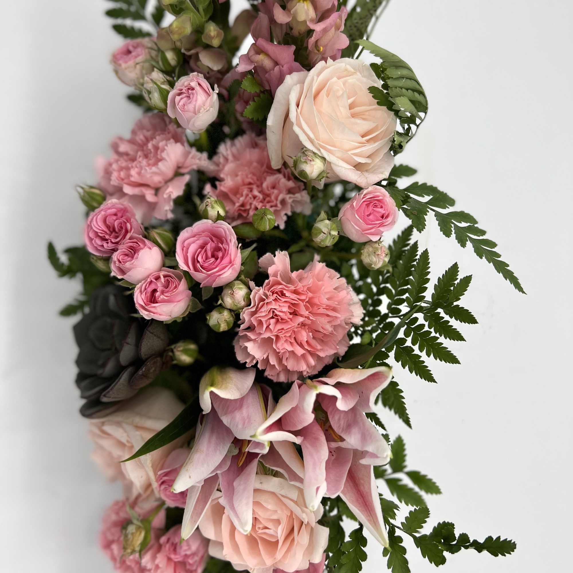 Pink and peach floral arrangement with roses, carnations, and lilies
