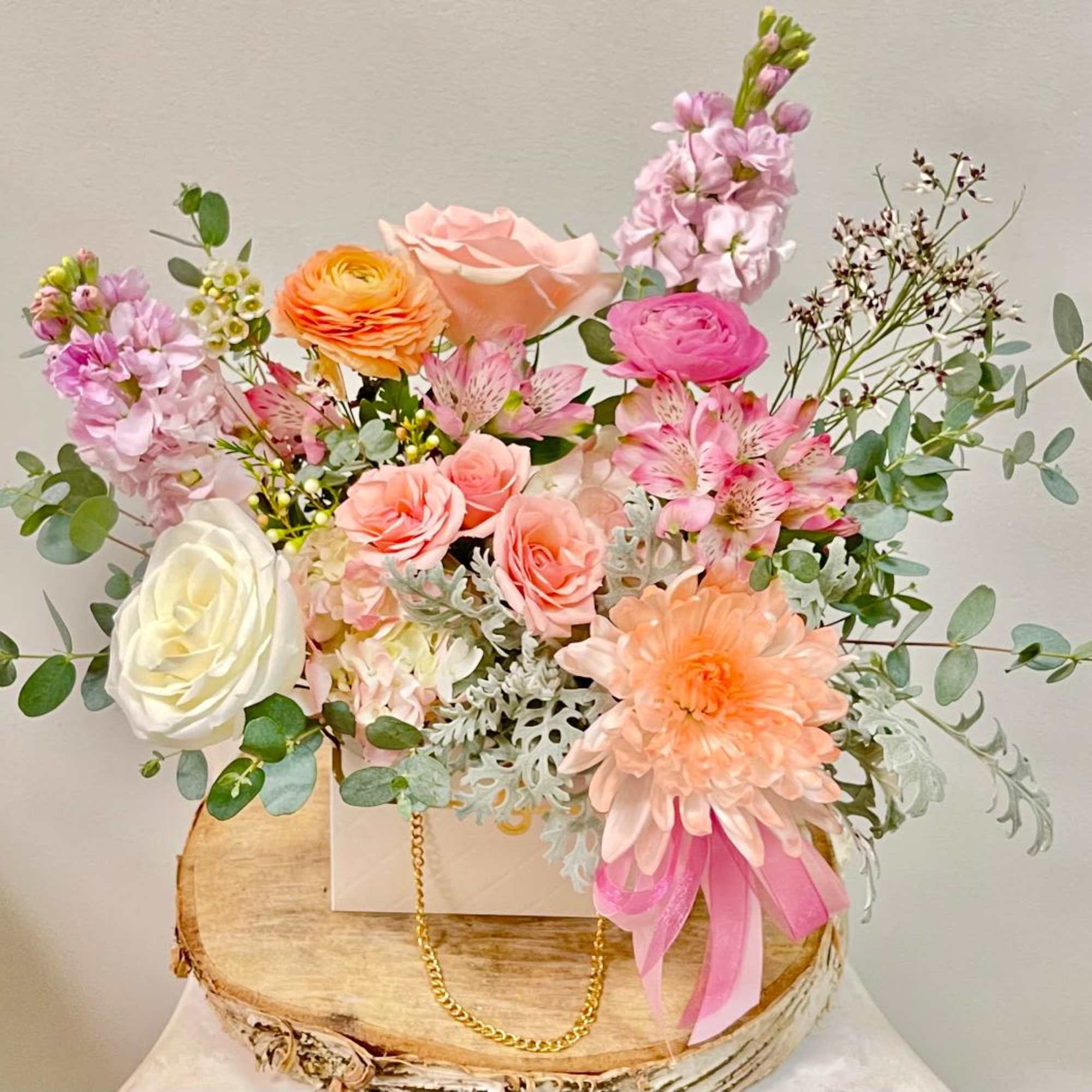 Mixed pastel flower arrangement in a white box with a pink ribbon
