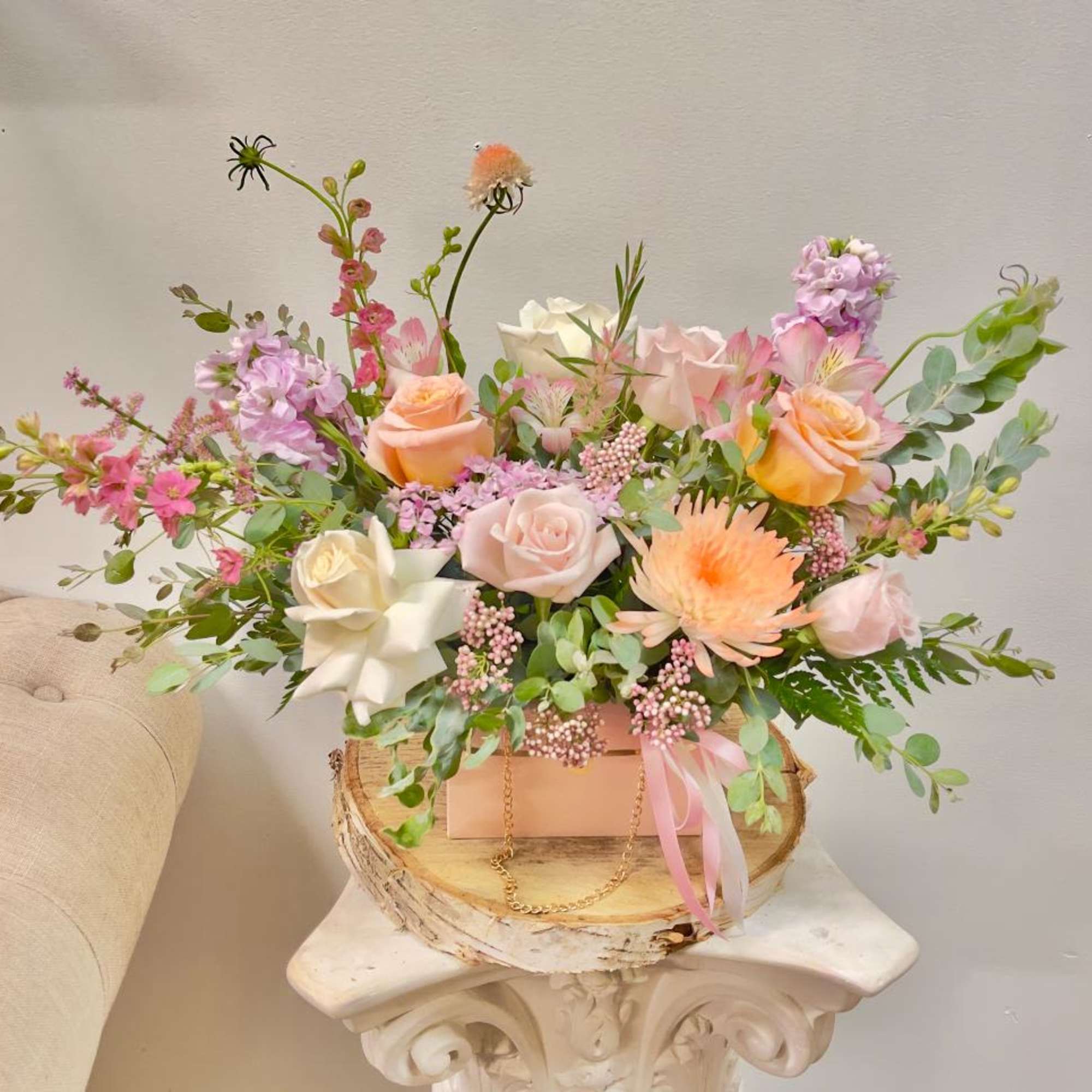 Pastel floral arrangement in a pink box with roses and mixed blooms