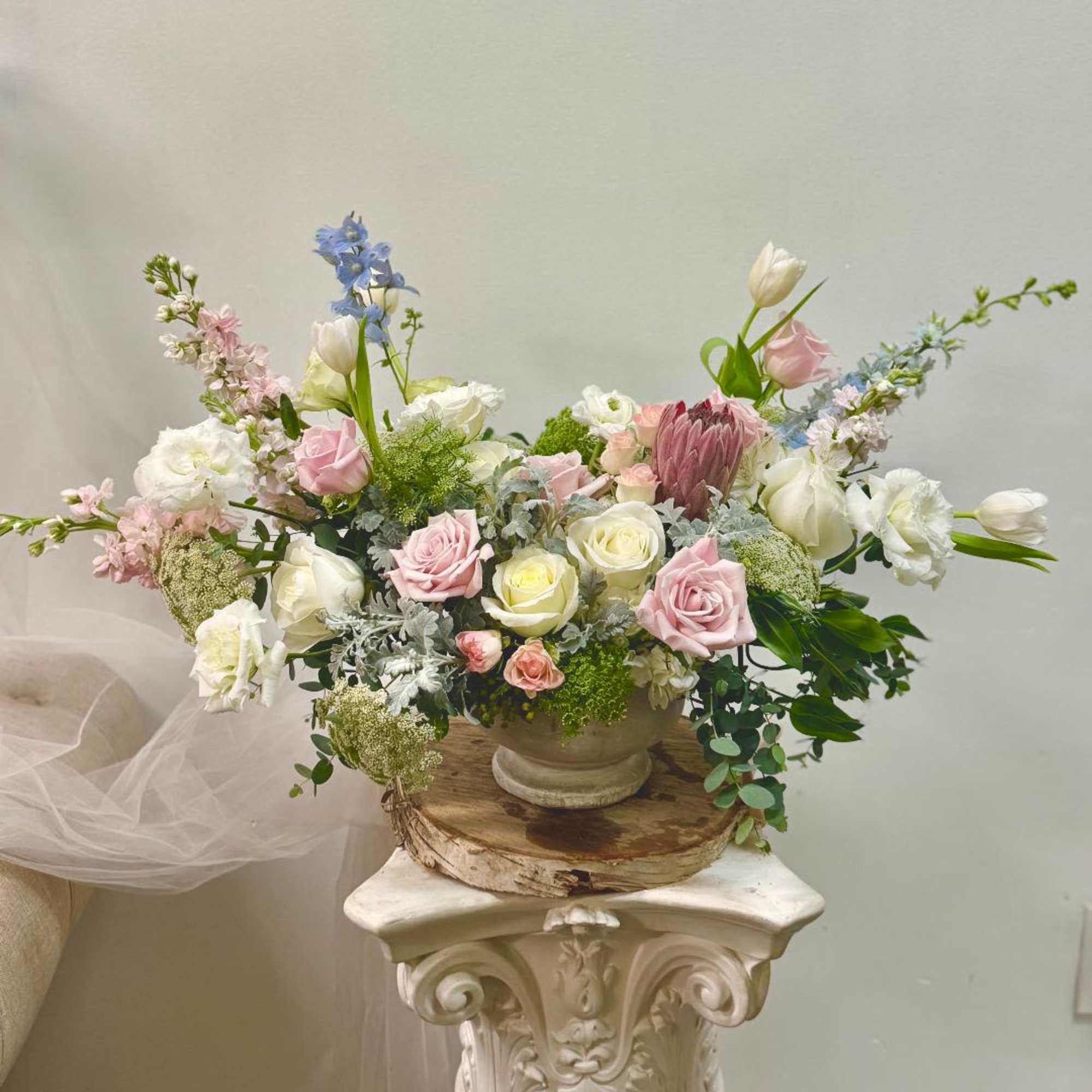 Pastel floral arrangement in a ceramic vase with roses and tulips