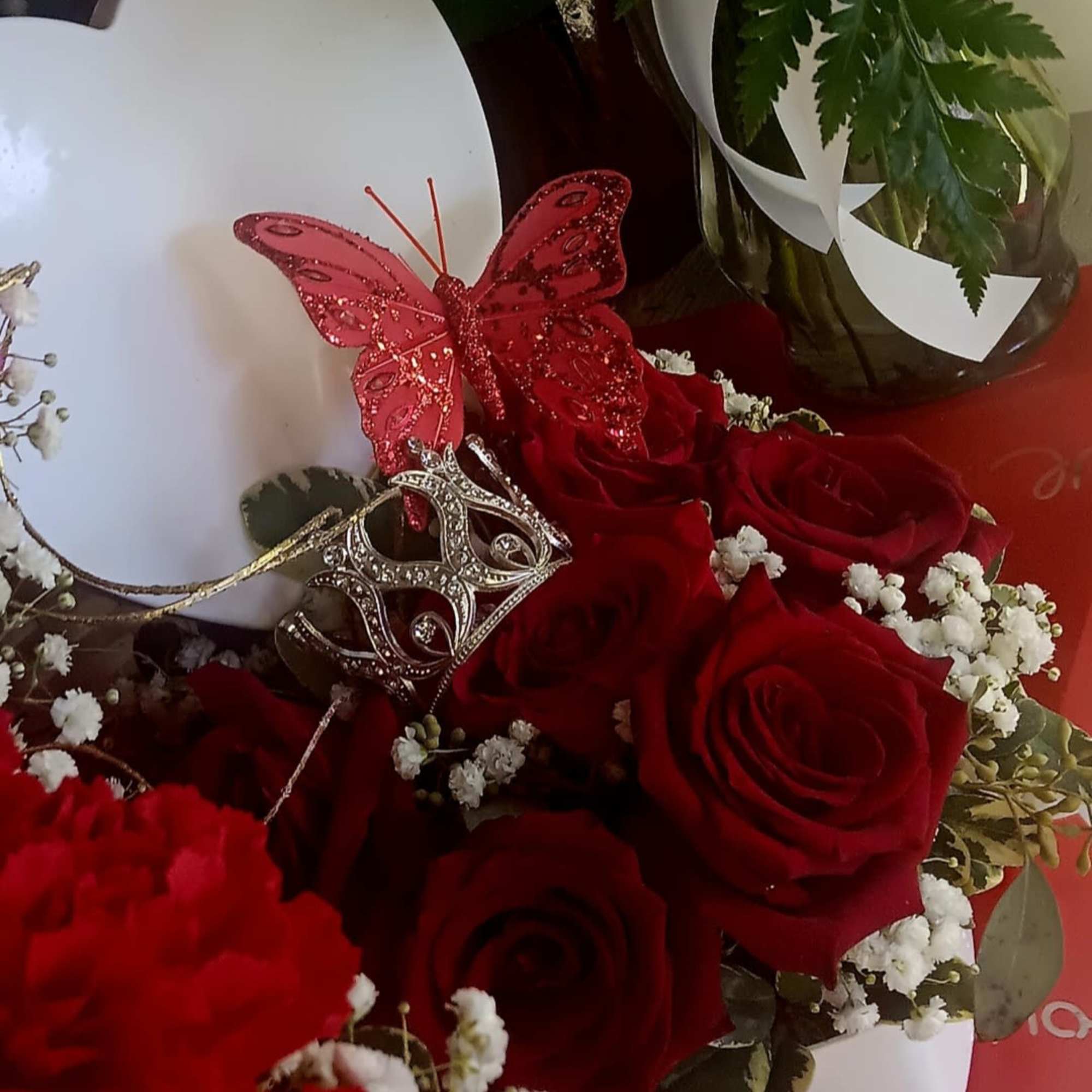 Red roses with baby’s breath and decorative butterfly picks in a white heart box