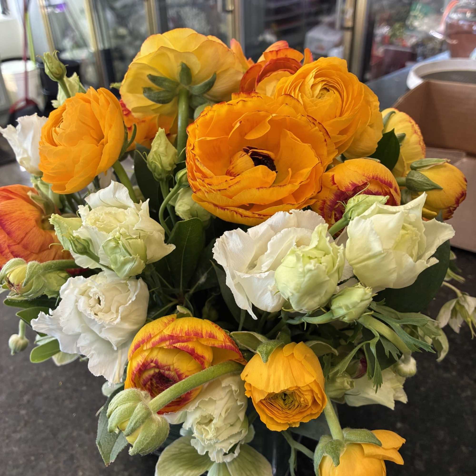 Ranunculus arranged in a lined Cube with a touch or White Lisianthus
