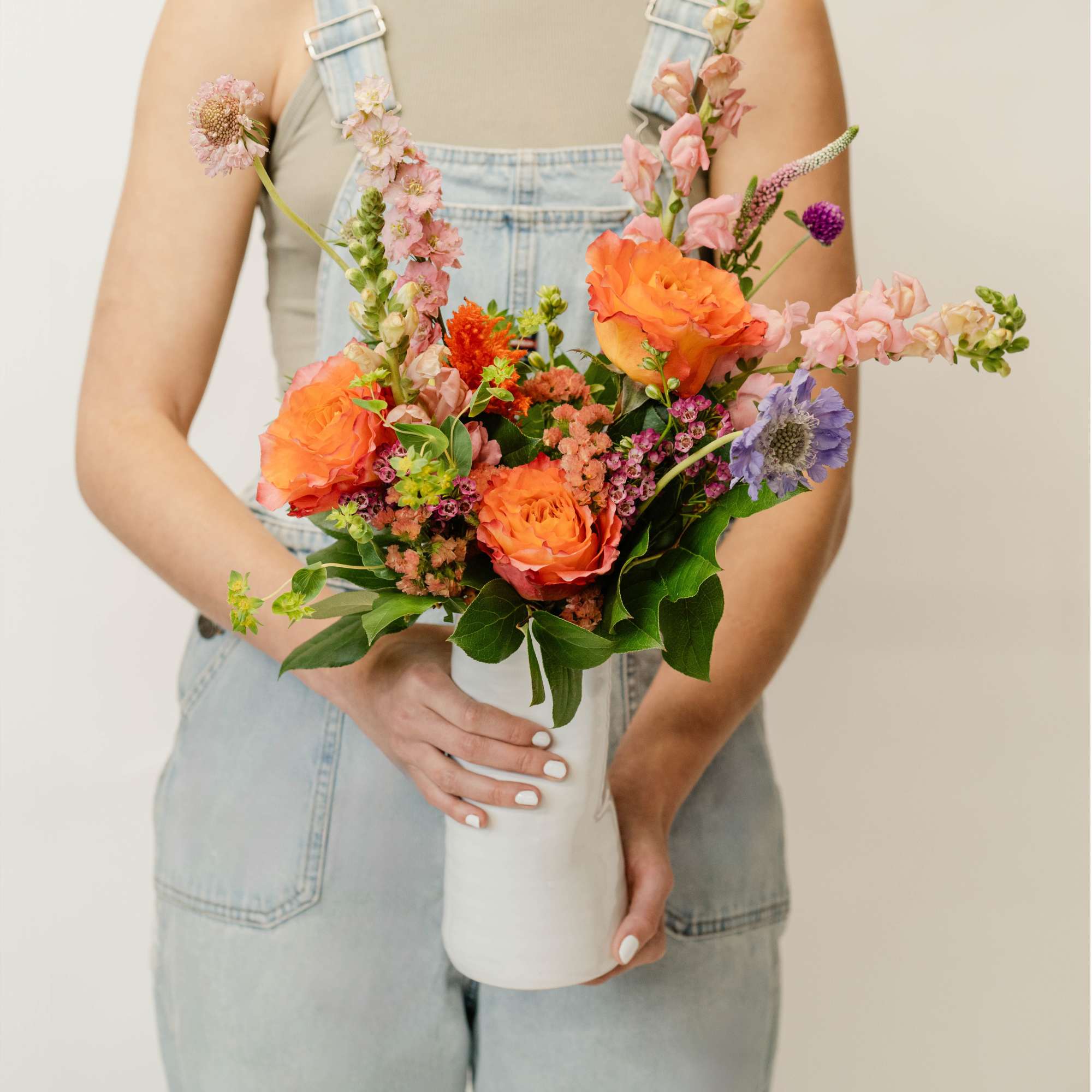 Woman holding a colorful bouquet in a white vase