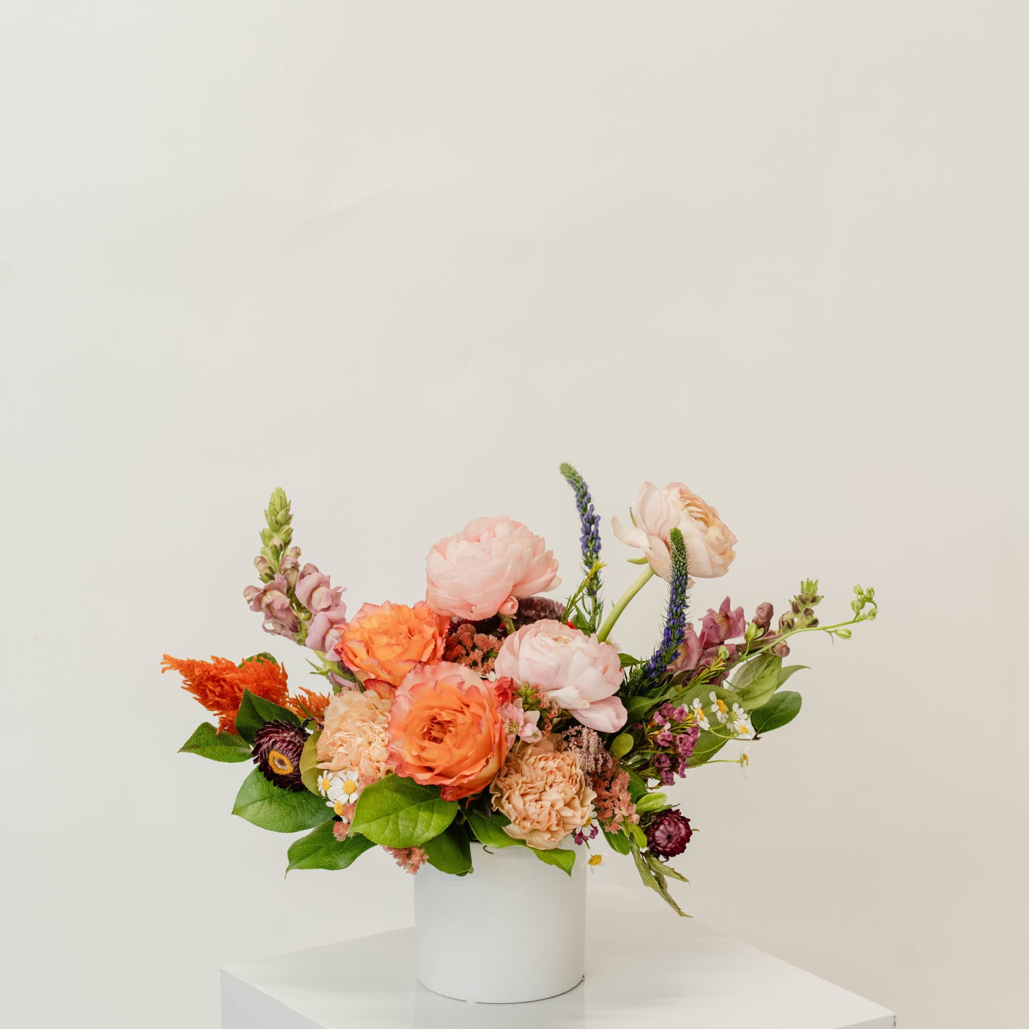 Colorful mixed flower arrangement in a white cylindrical vase