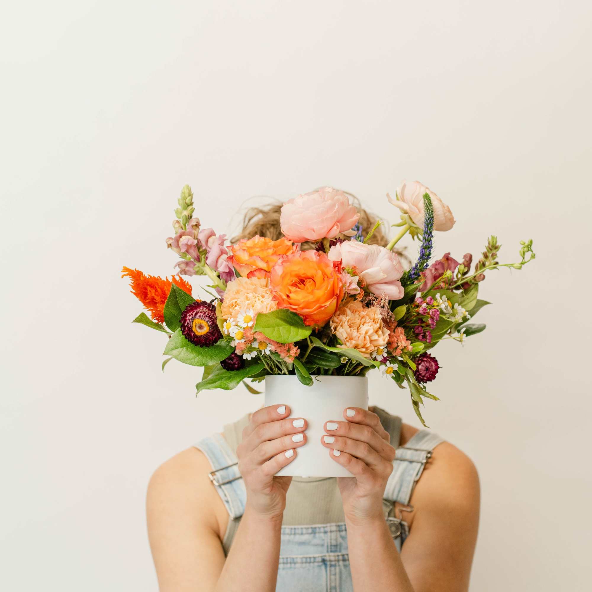 Mixed bouquet in a white vase held in front of a person