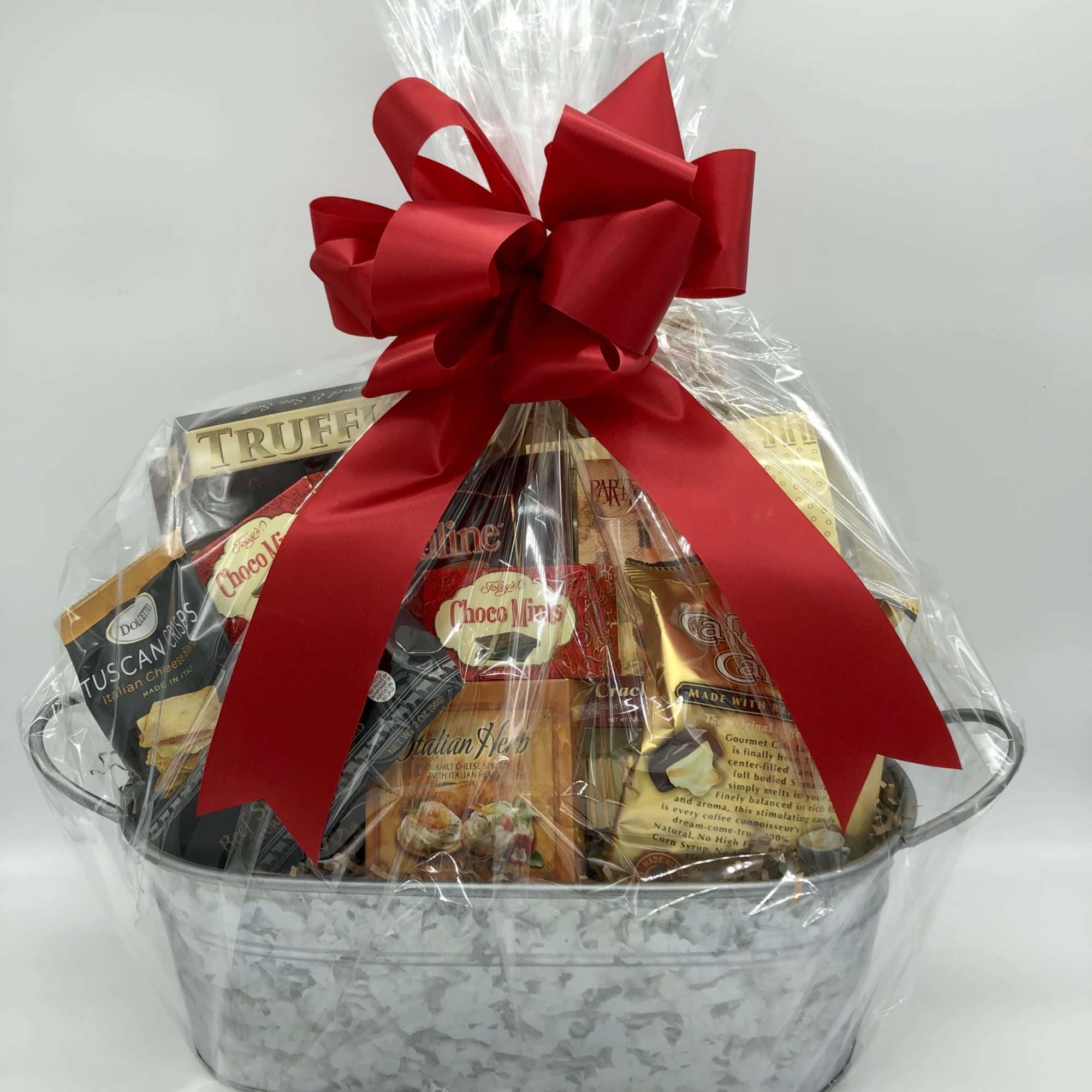 Gift basket of assorted snacks wrapped in clear cellophane with a red bow