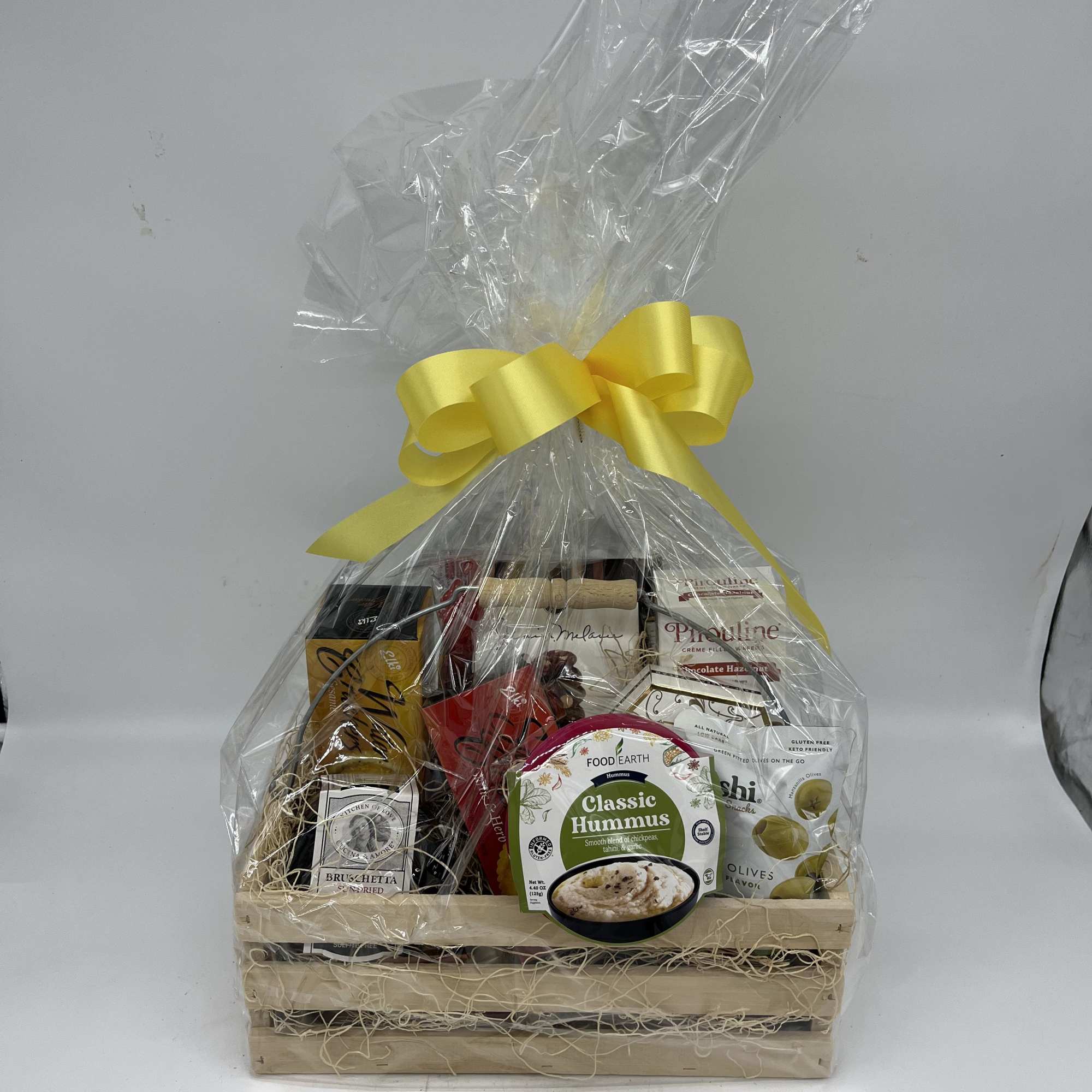 Gift basket of assorted snacks wrapped in clear cellophane with a yellow bow