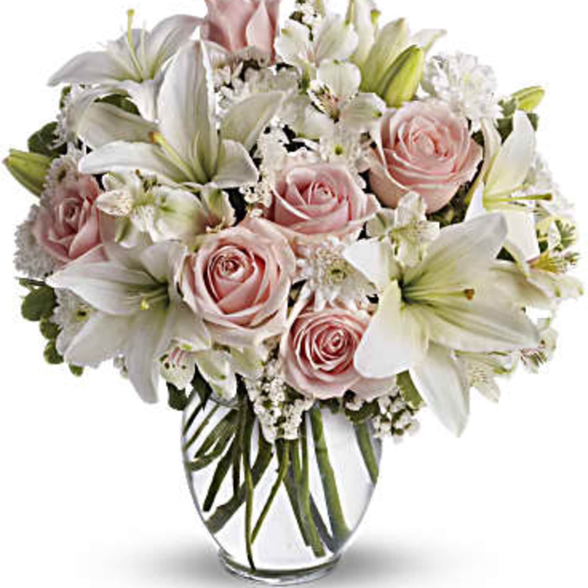 Arrangement of white lilies and pale pink roses in a clear glass vase