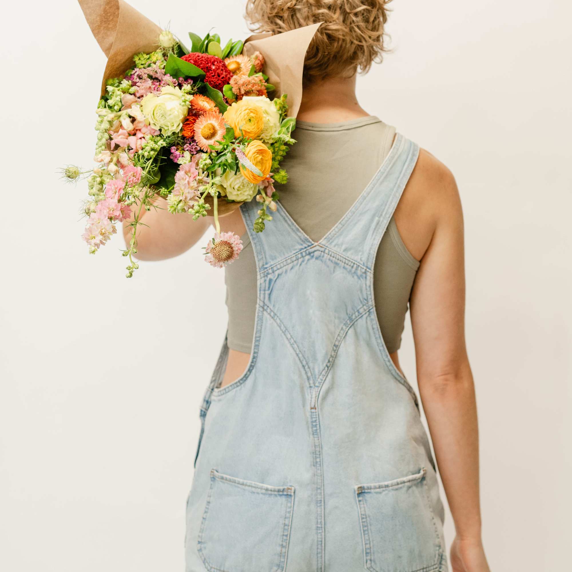 Person holding a colorful mixed bouquet wrapped in brown paper