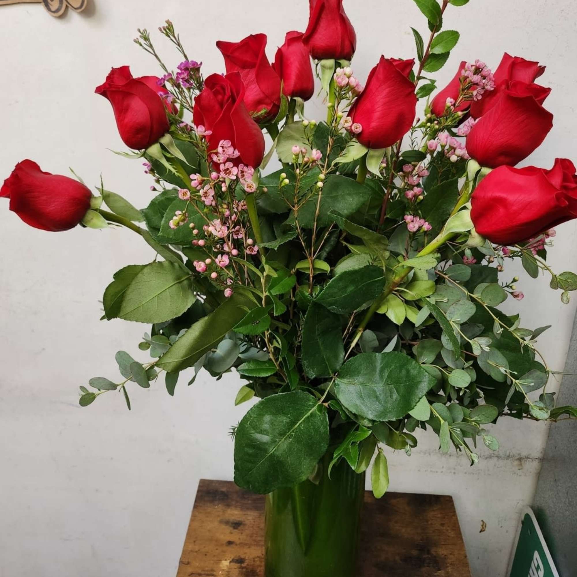 Bouquet of red roses with pink filler flowers in a green glass vase