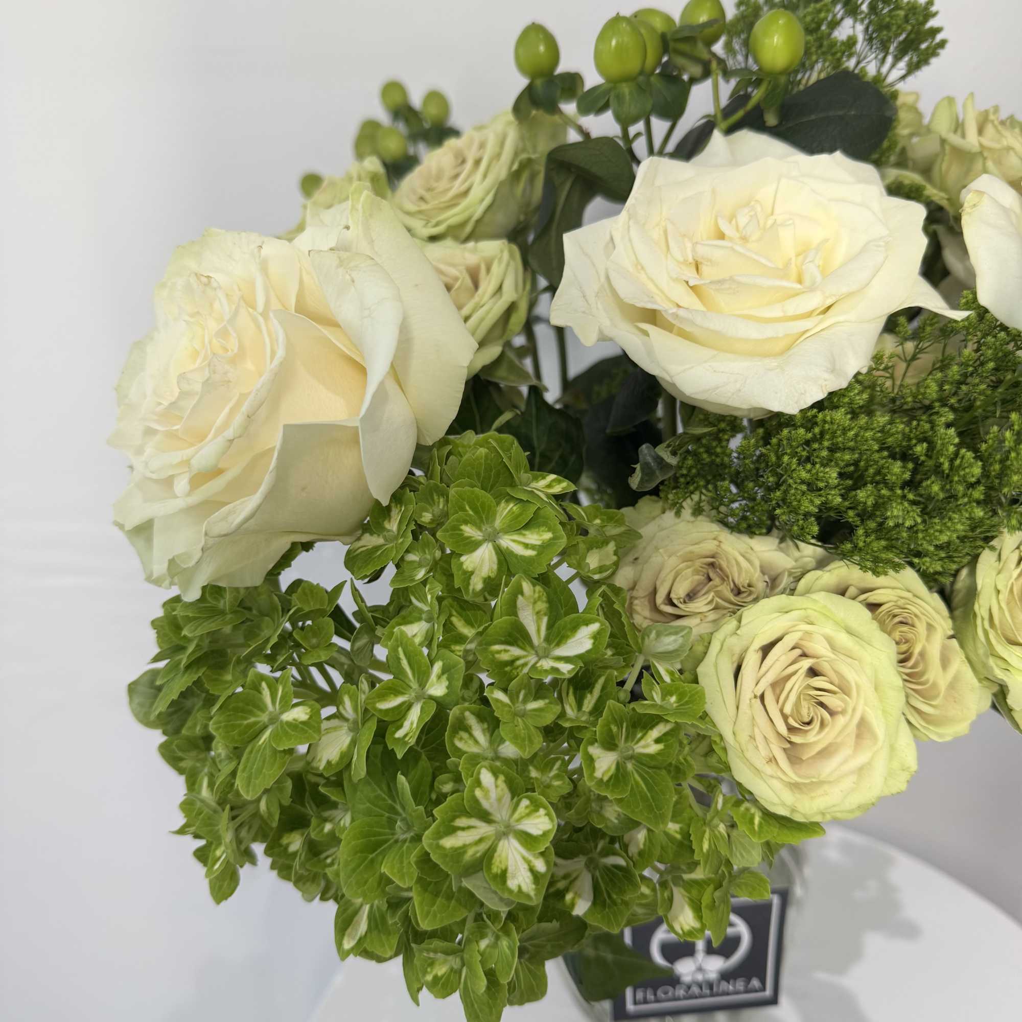 Cream roses and green blooms in a glass vase