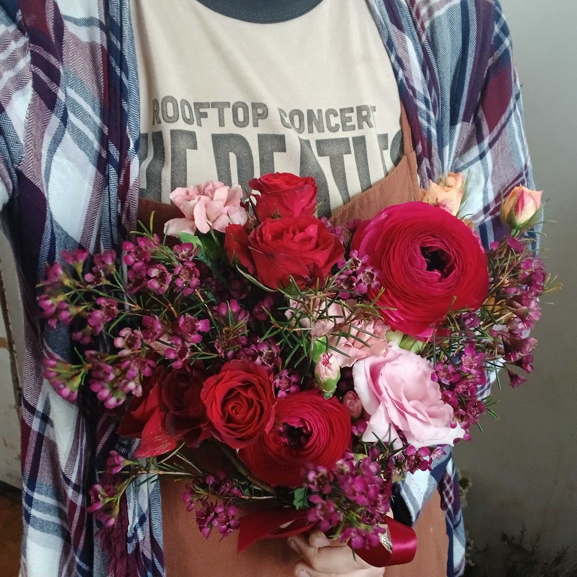 Handheld bouquet of red and pink roses with magenta blooms