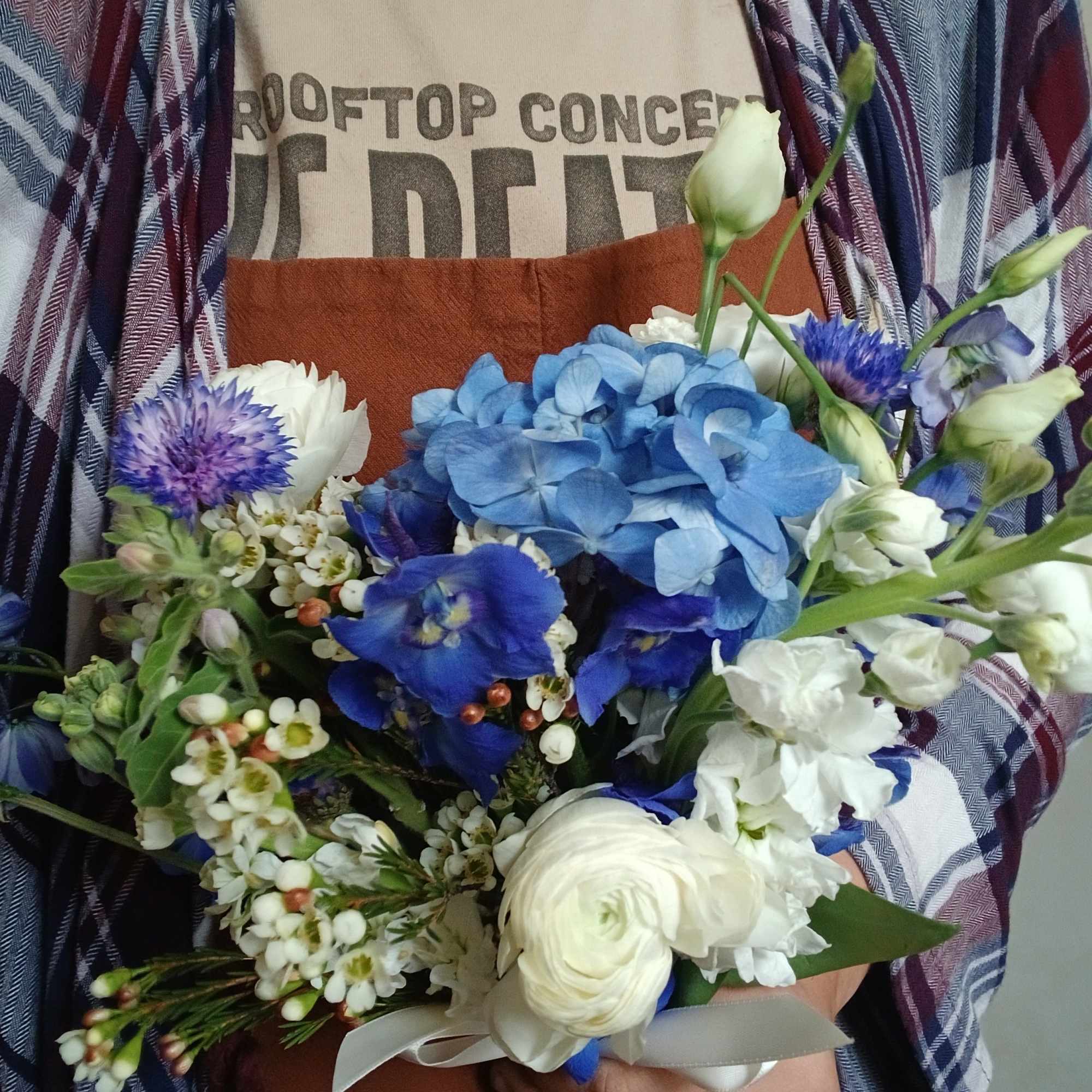 Handheld bouquet of blue and white flowers with a ribbon tie