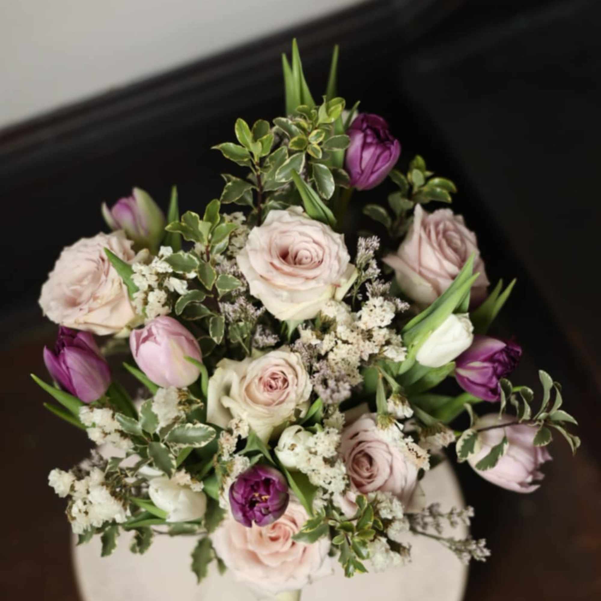 Bouquet of pale pink roses and purple tulips with white filler flowers