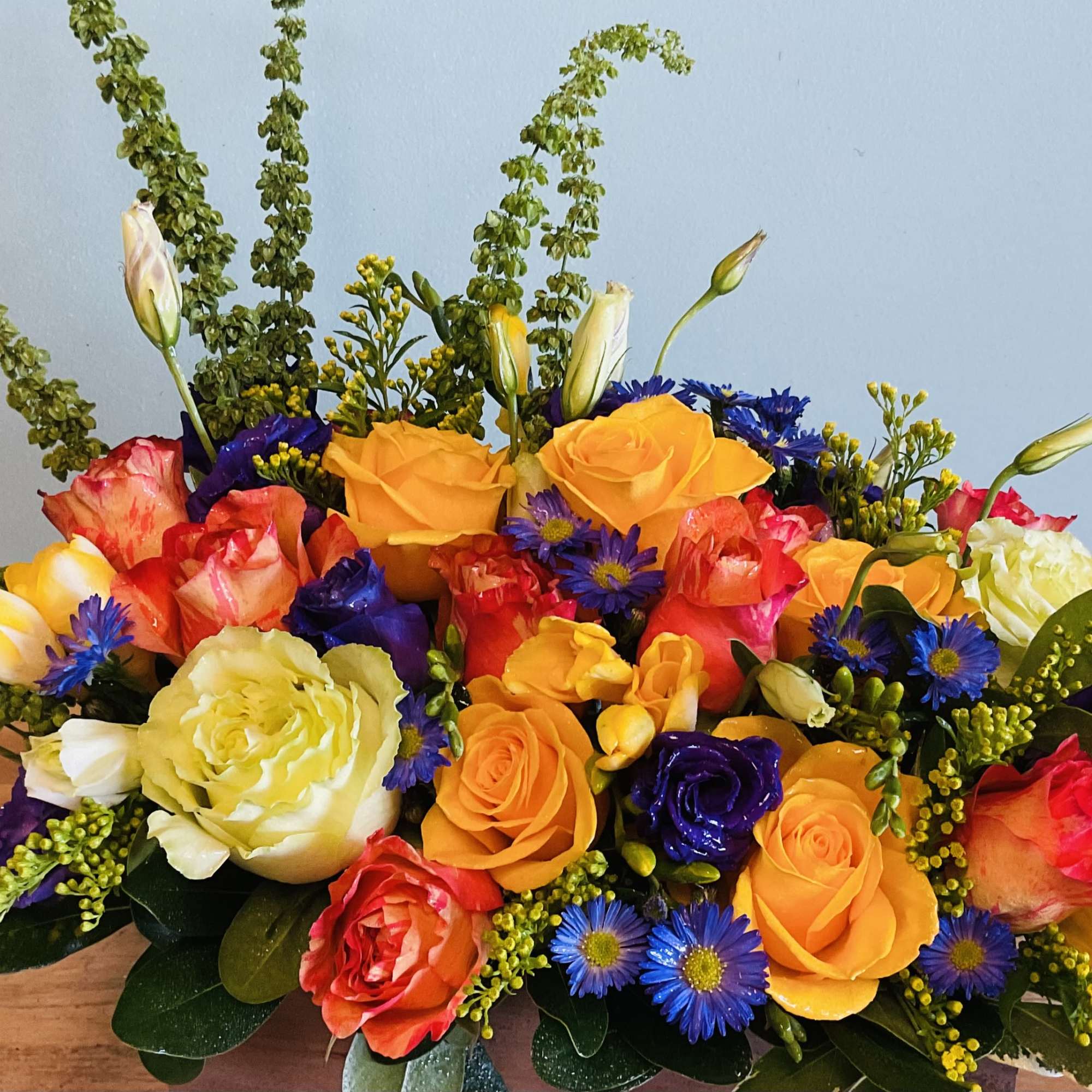 Colorful bouquet of roses, tulips, and blue daisies in a low arrangement