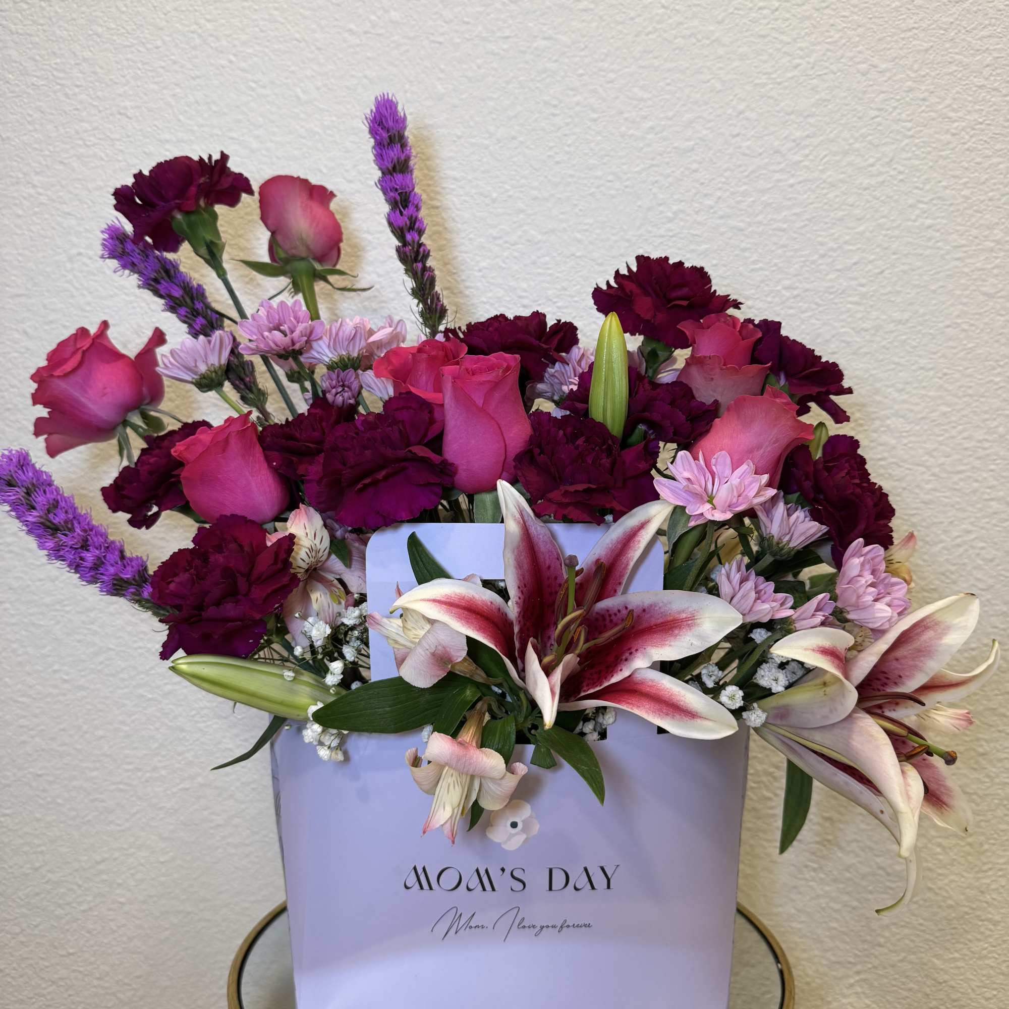 Bouquet of pink roses, lilies, and purple carnations in a gift box