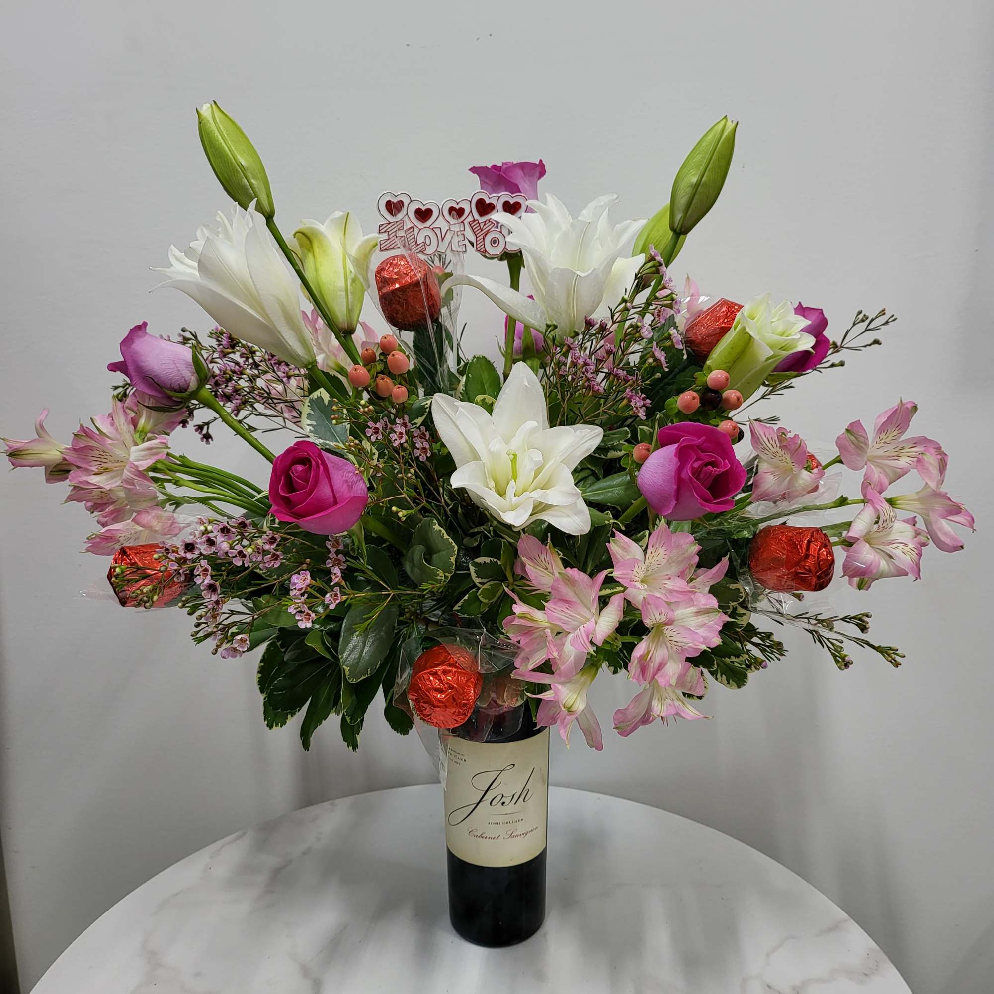Bouquet of lilies, roses, and pink alstroemeria in a wine bottle vase