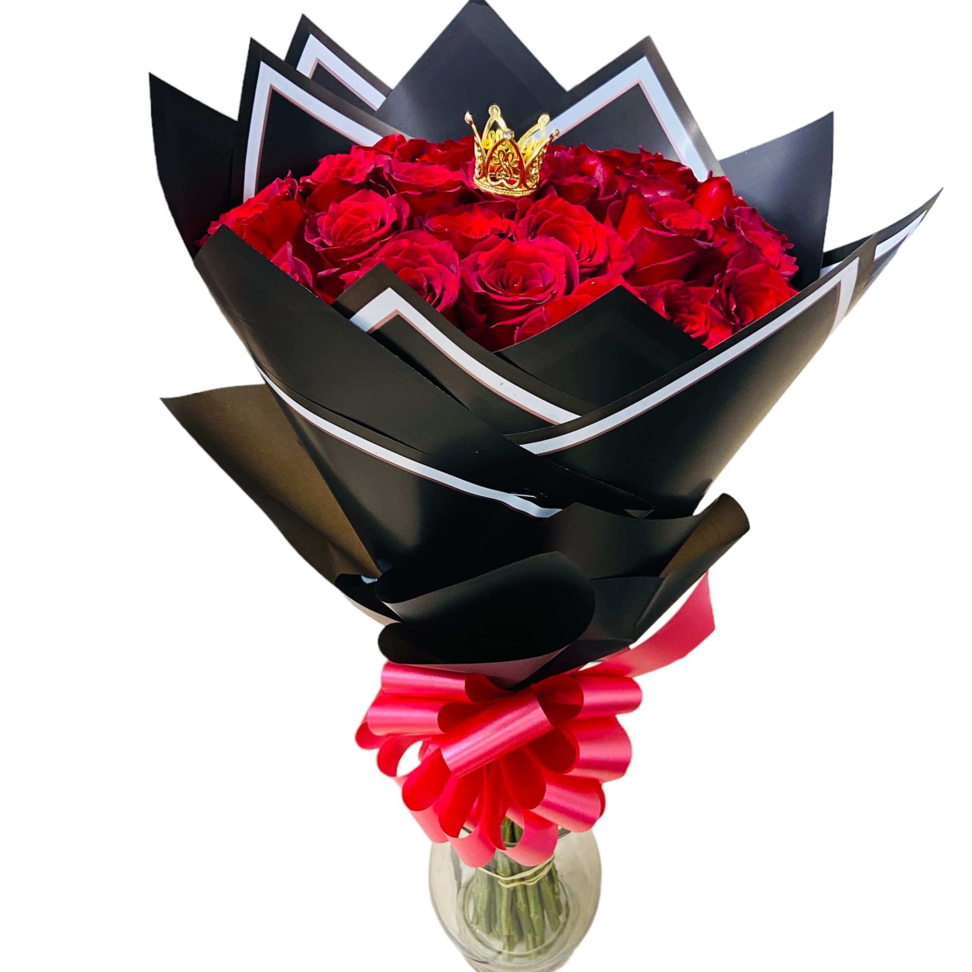 Bouquet of red roses wrapped in black paper with a pink ribbon in a glass vase