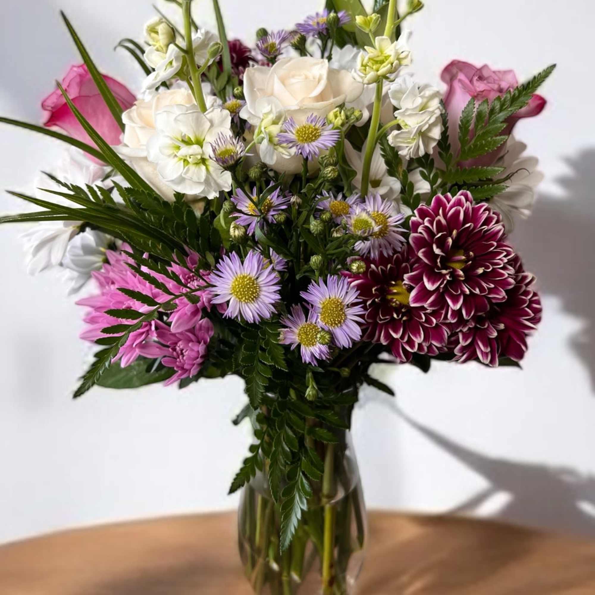 Mixed bouquet of white, pink, and purple flowers in a clear glass vase