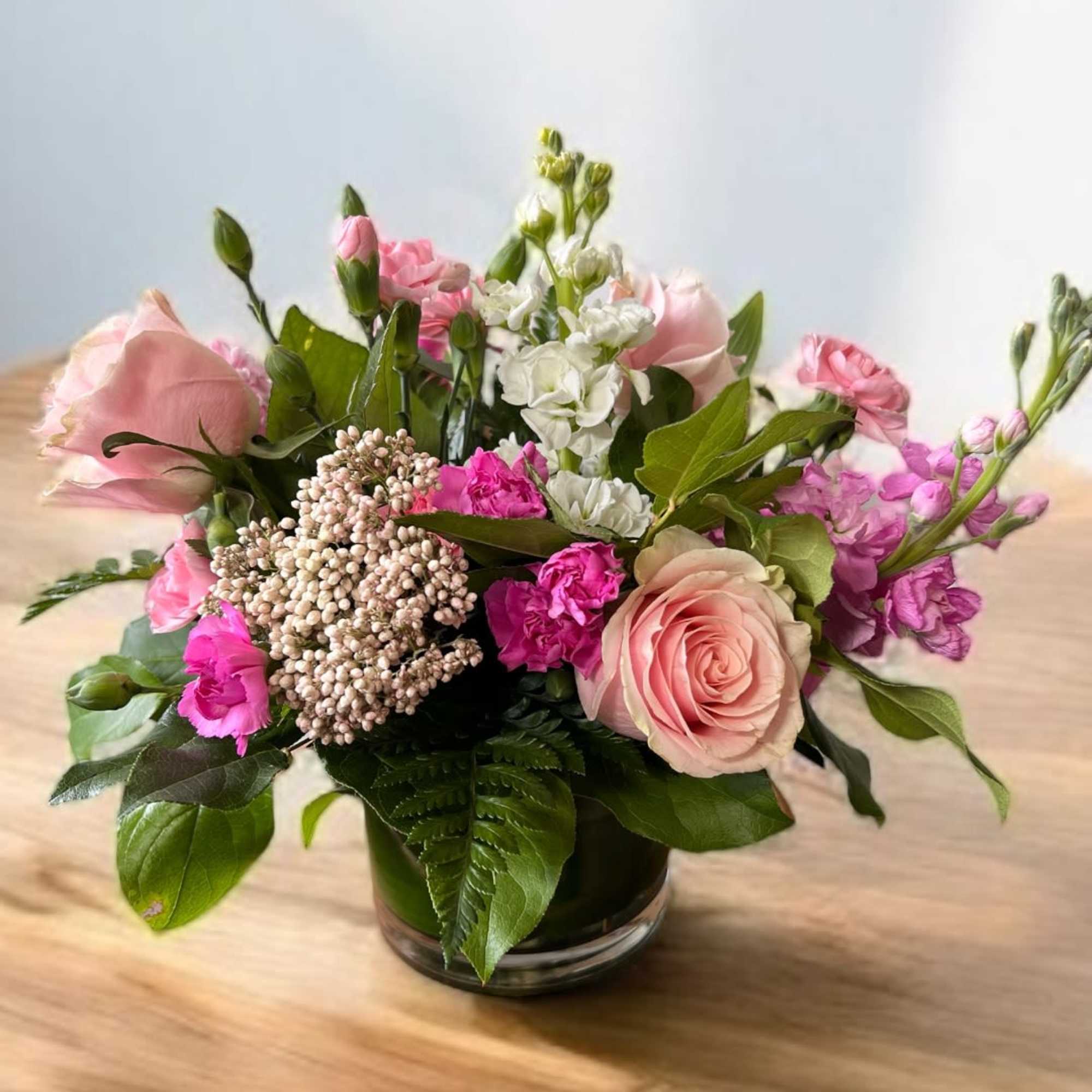 Pink and white mixed flower arrangement in a low glass vase
