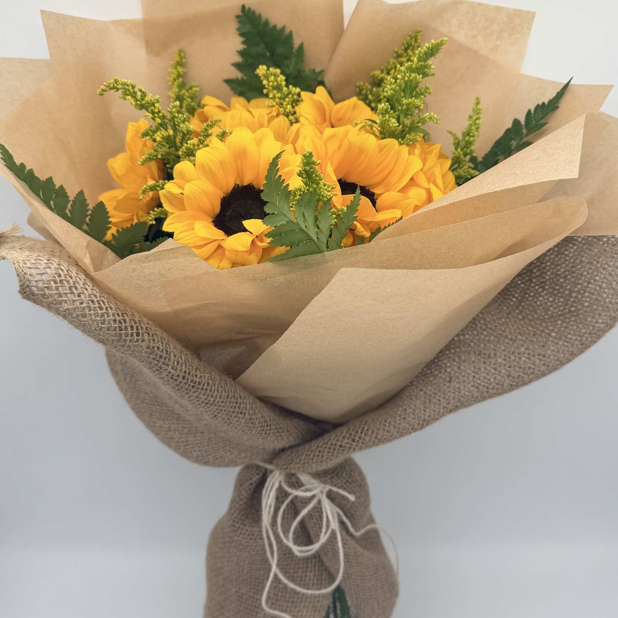 Bouquet of yellow sunflowers wrapped in brown paper and burlap