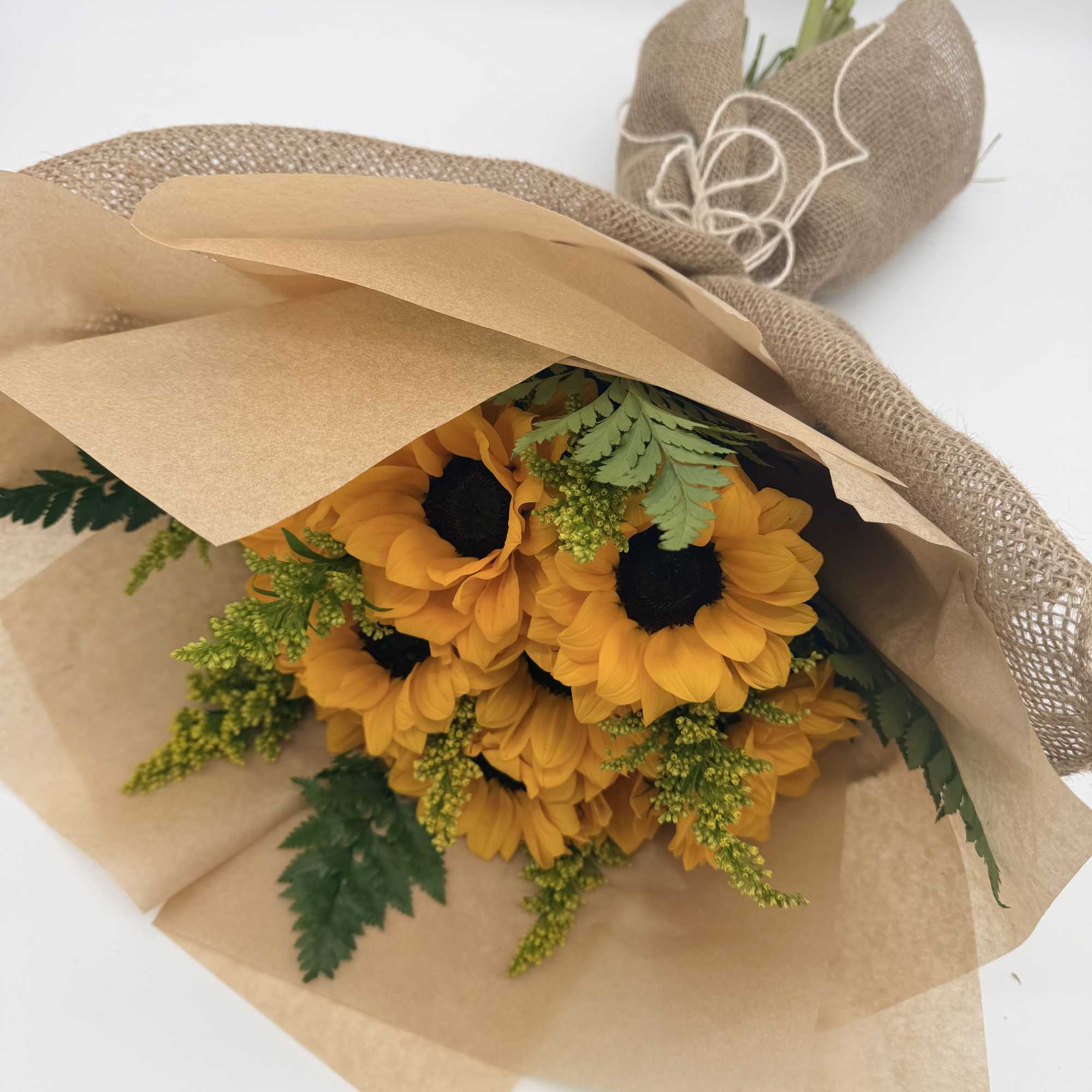 Bouquet of yellow sunflowers wrapped in brown paper and burlap