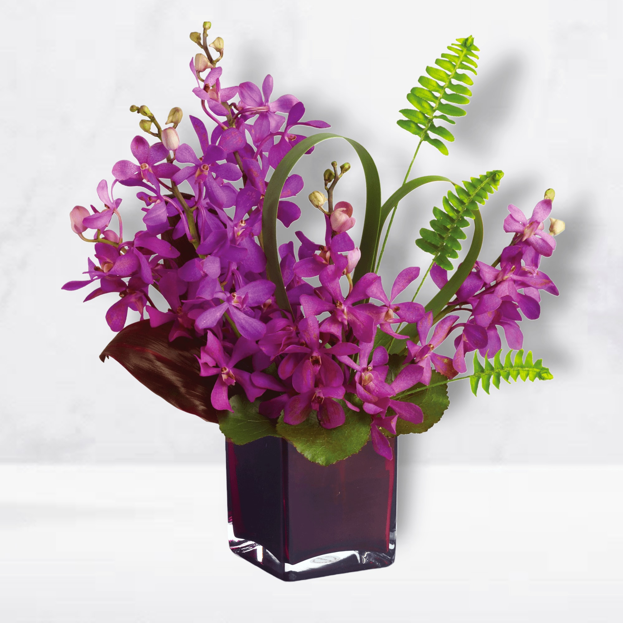 Purple orchid arrangement in a dark glass vase