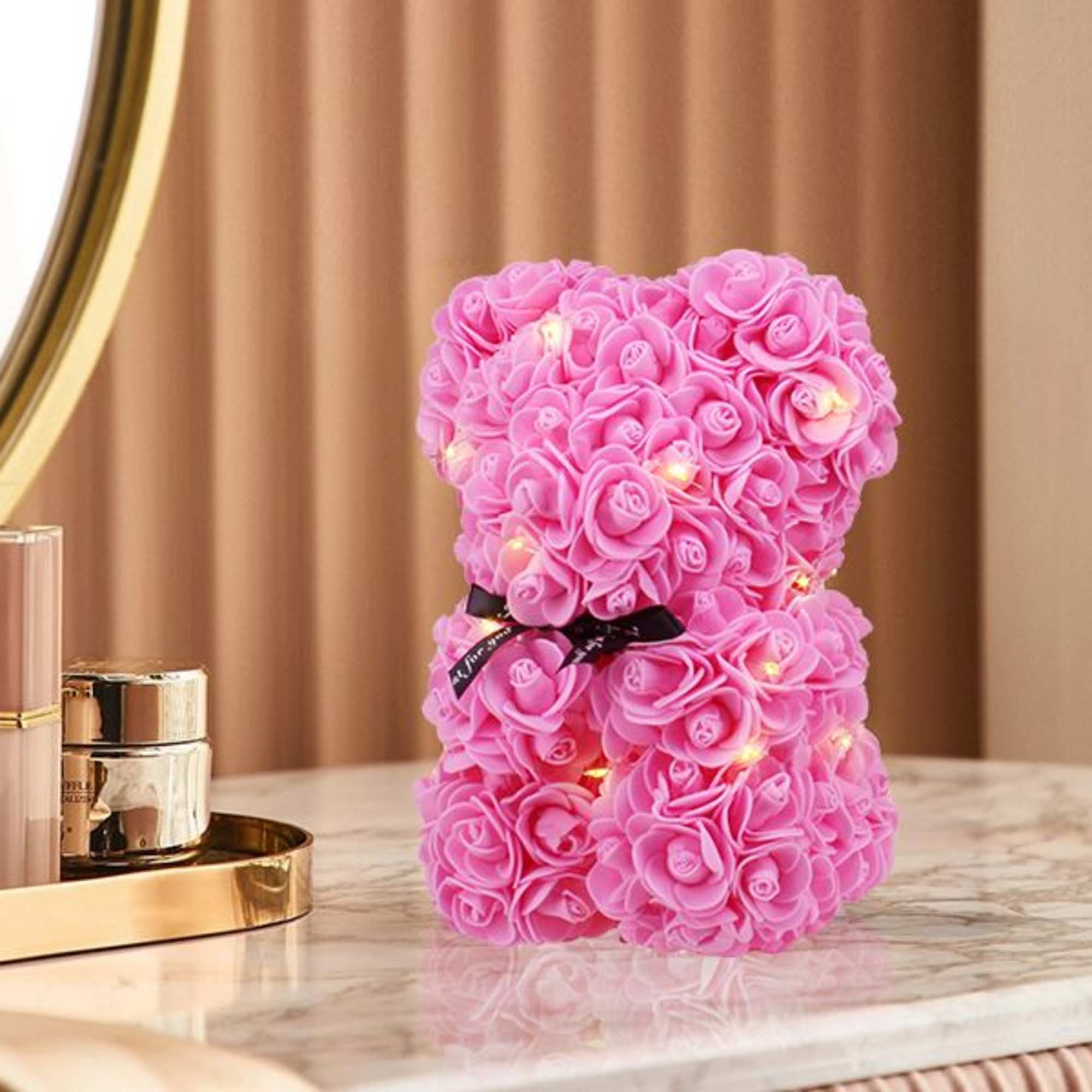 Pink rose teddy bear with small lights on a tabletop