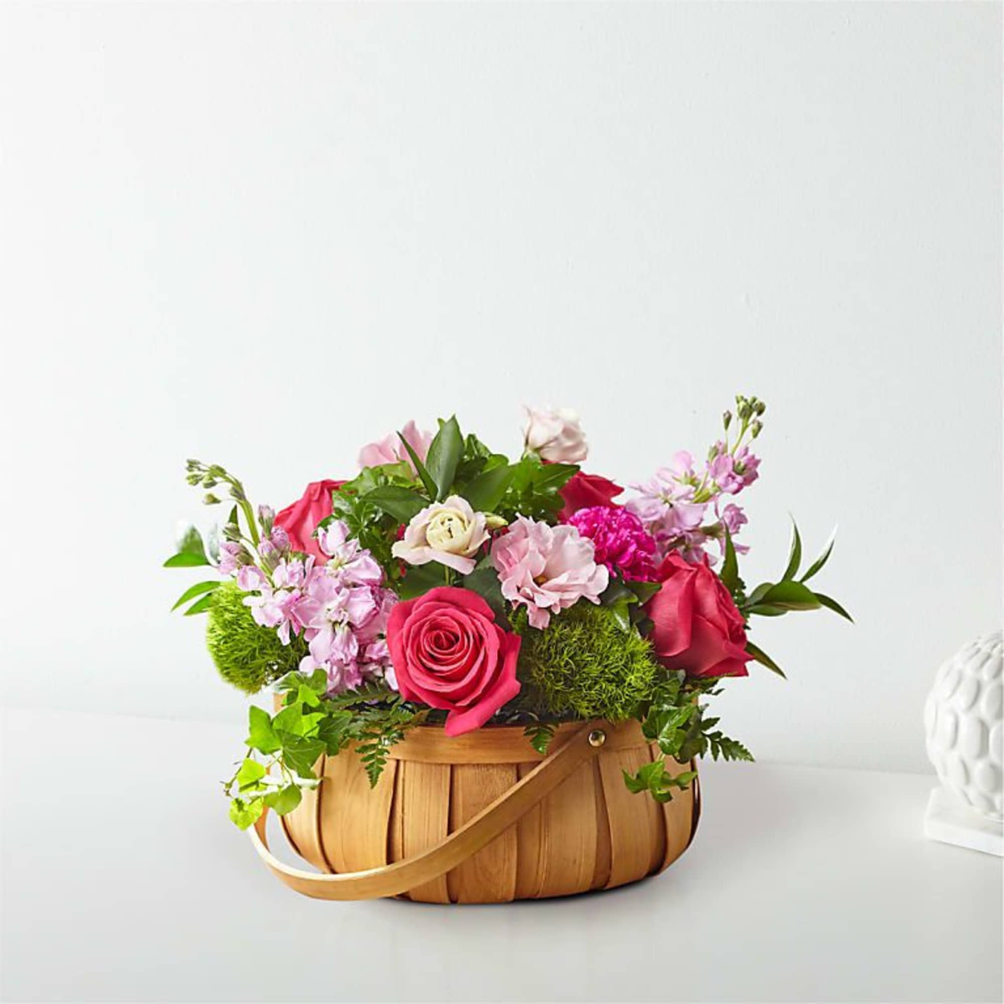 Pink and red roses arranged in a woven basket