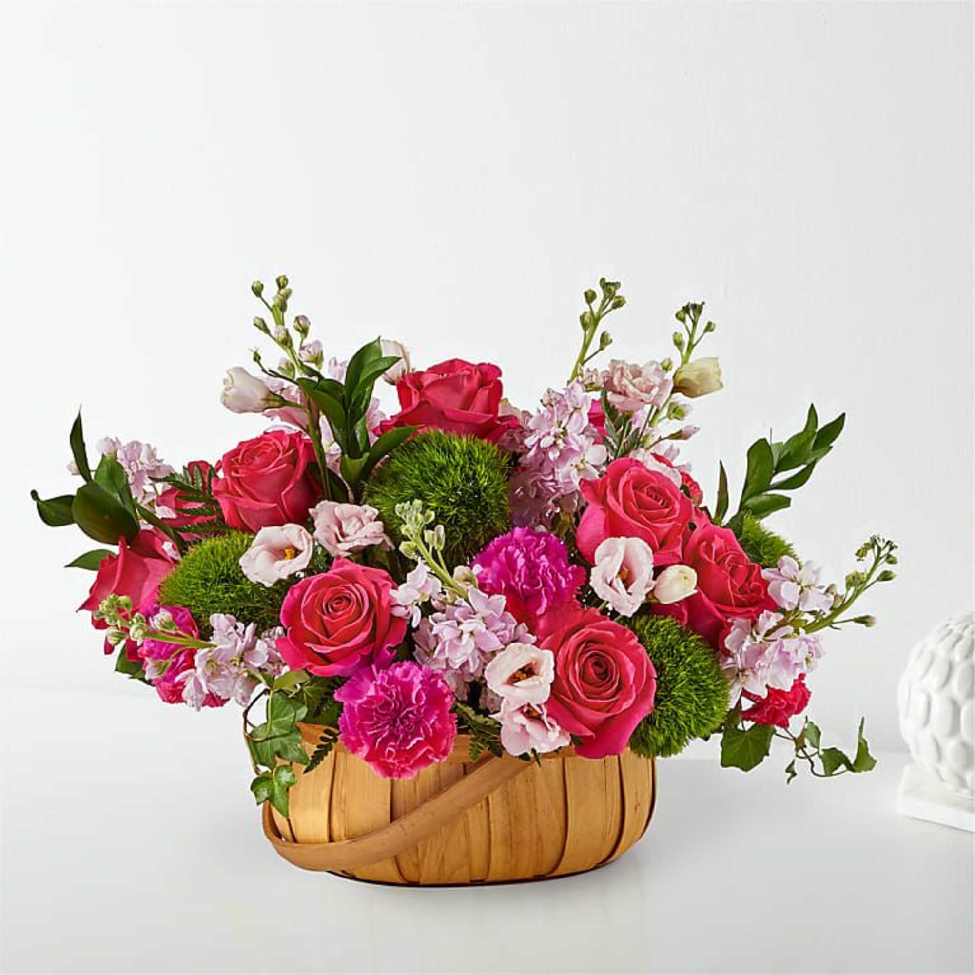 Pink roses and carnations in a woven basket