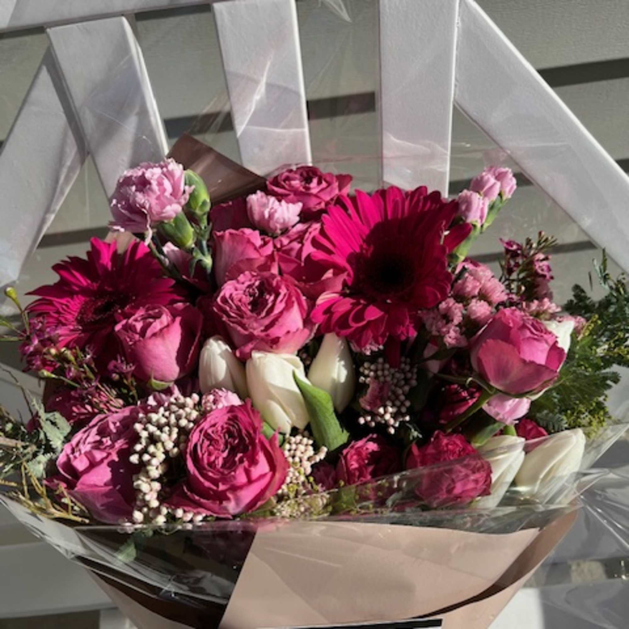 Pink and white mixed bouquet wrapped in paper and clear plastic