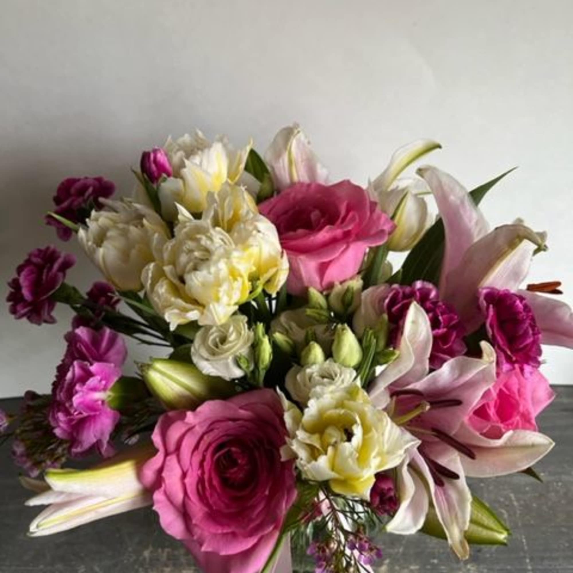 Bouquet of pink roses, lilies, and white blooms on a dark surface