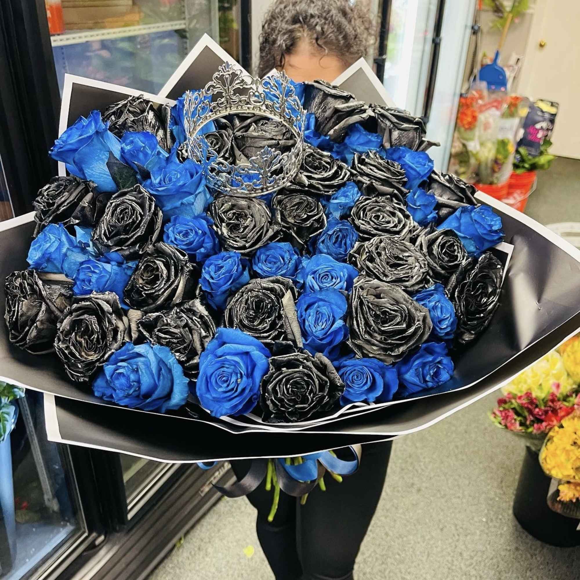 Large bouquet of blue and black roses with a silver crown topper