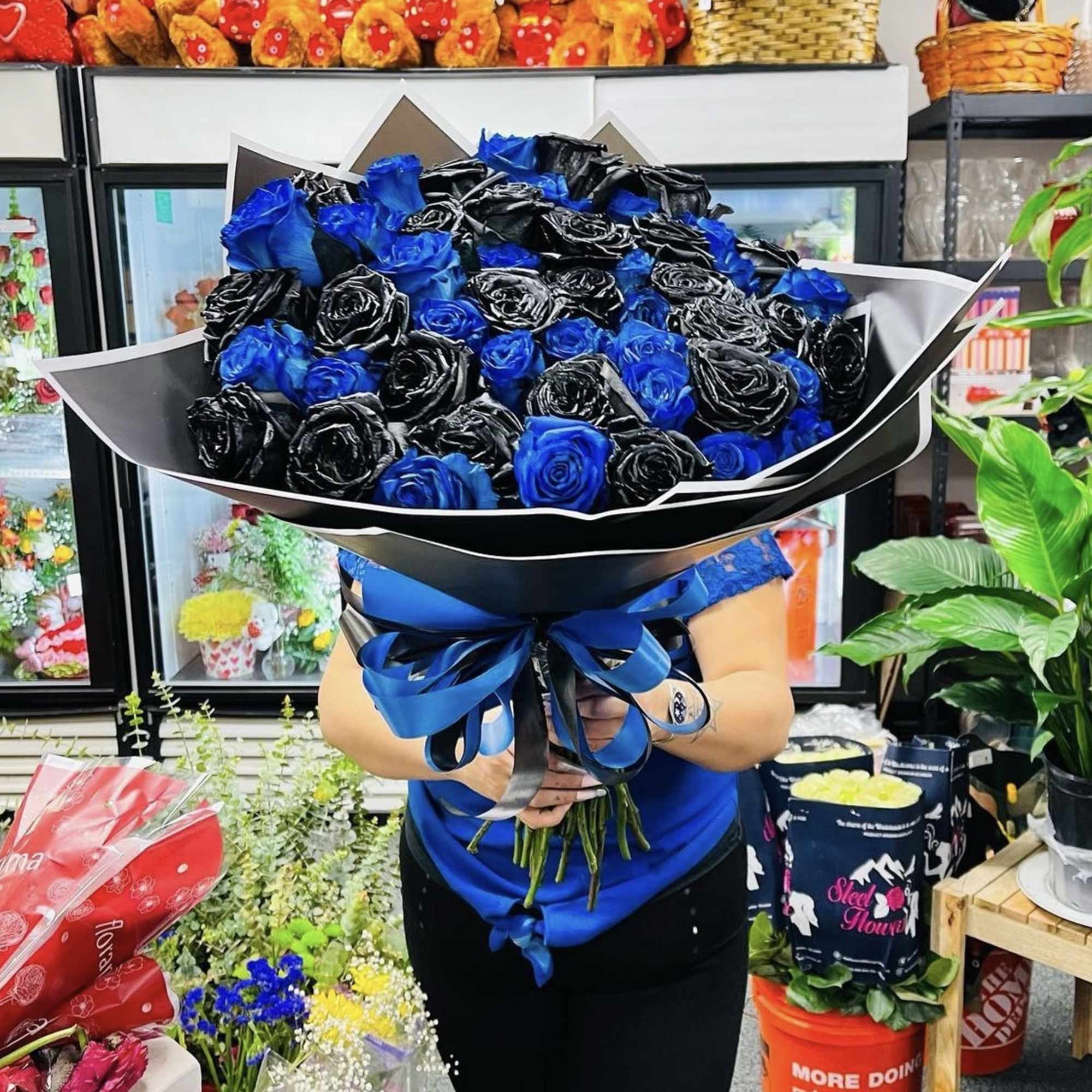 Large bouquet of blue and black roses wrapped in black paper with a blue ribbon