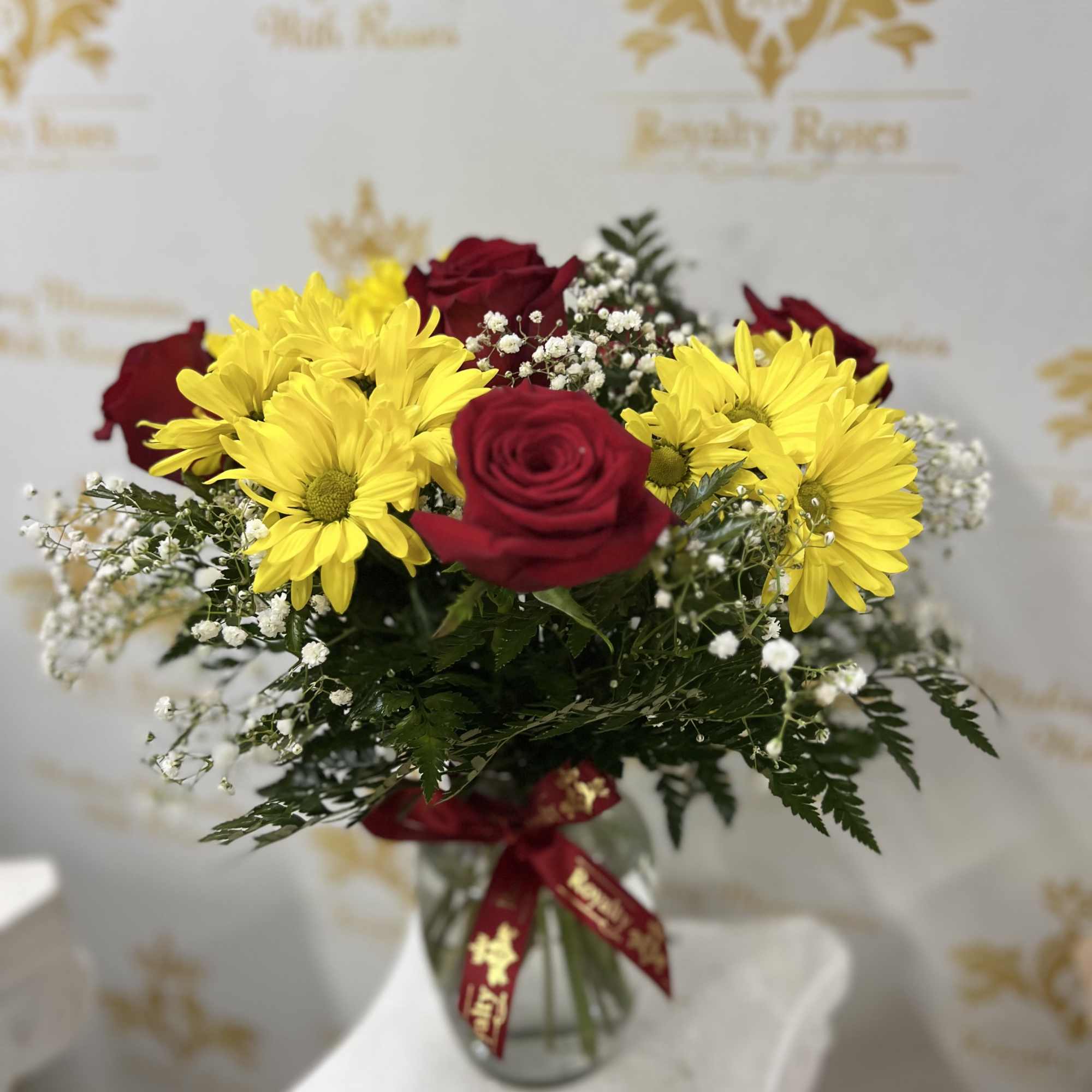 Sunlit yellow daisies paired with rich red roses give this flower arrangement
