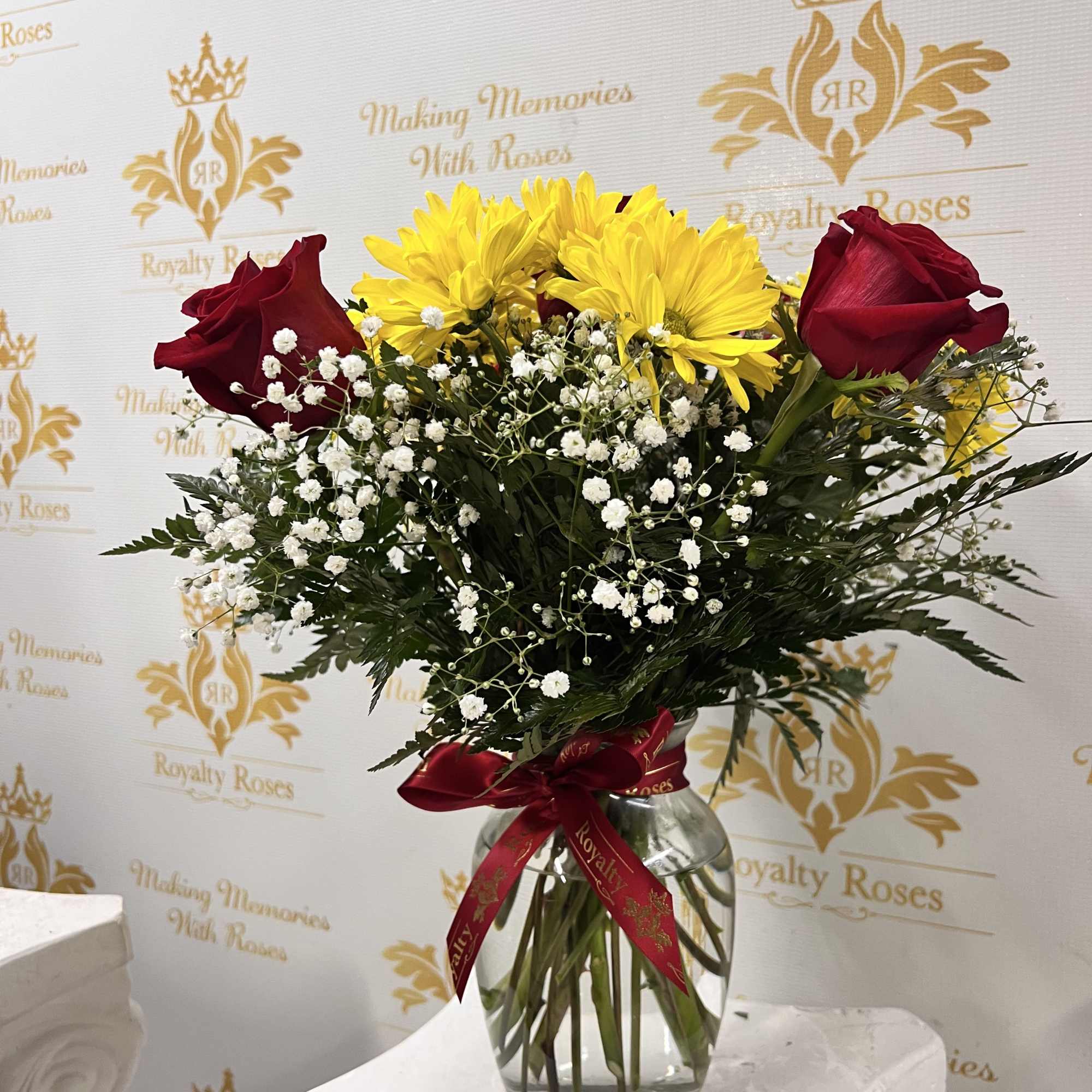 Sunlit yellow daisies paired with rich red roses give this flower arrangement
