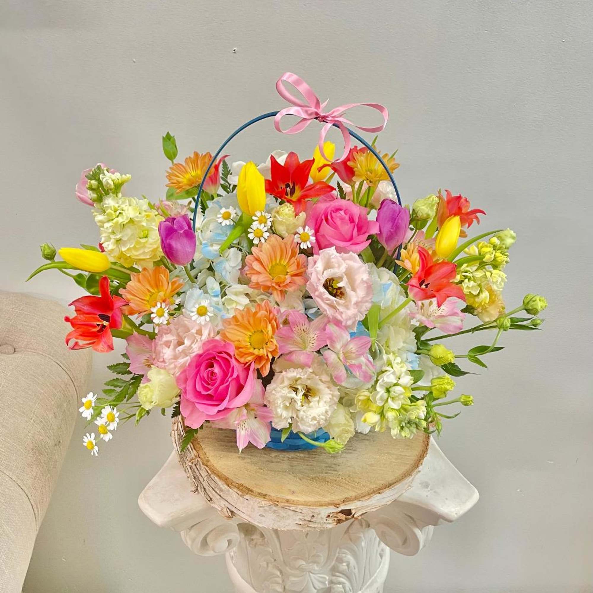 Colorful mixed flower basket with a pink ribbon handle