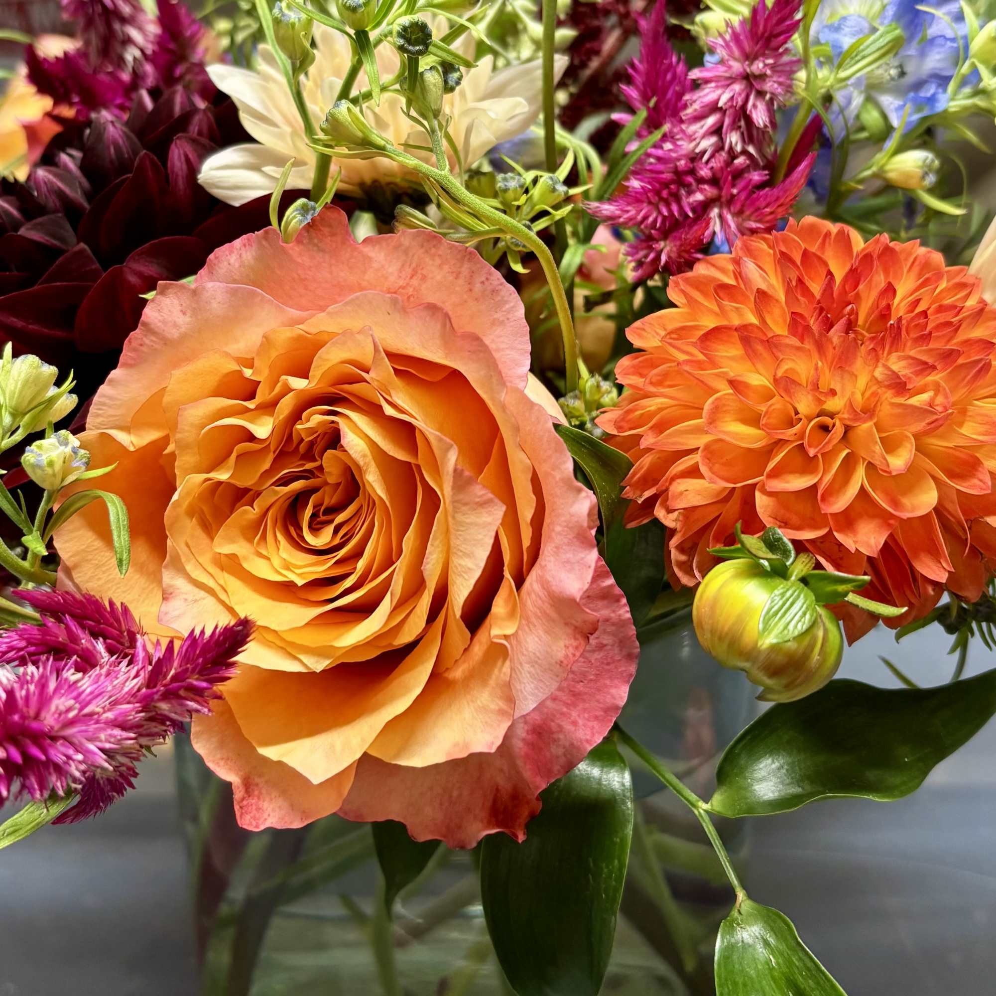 Colorful mixed bouquet in a glass vase with orange and pink blooms