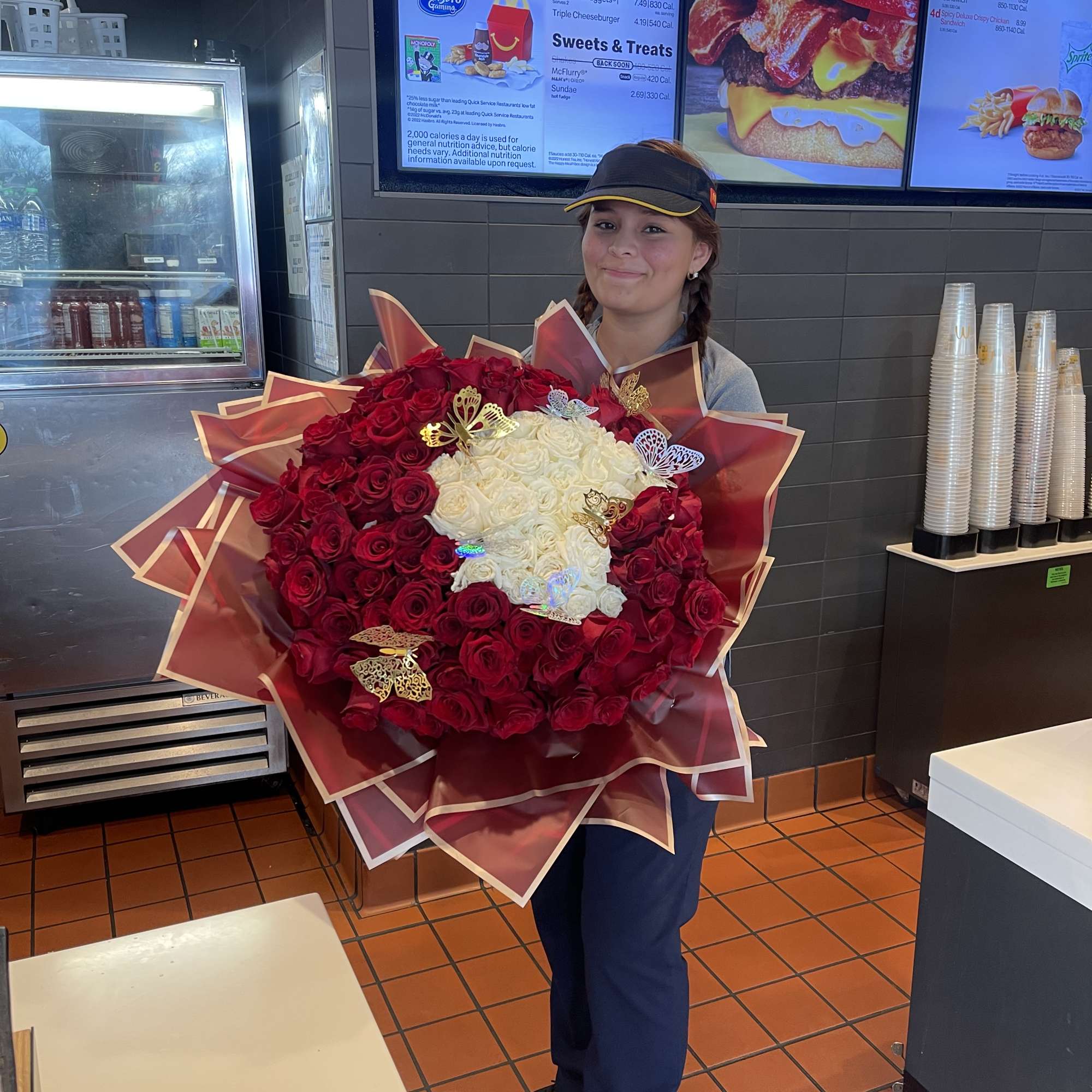 Person holding a large bouquet of red and white roses with butterfly decorations