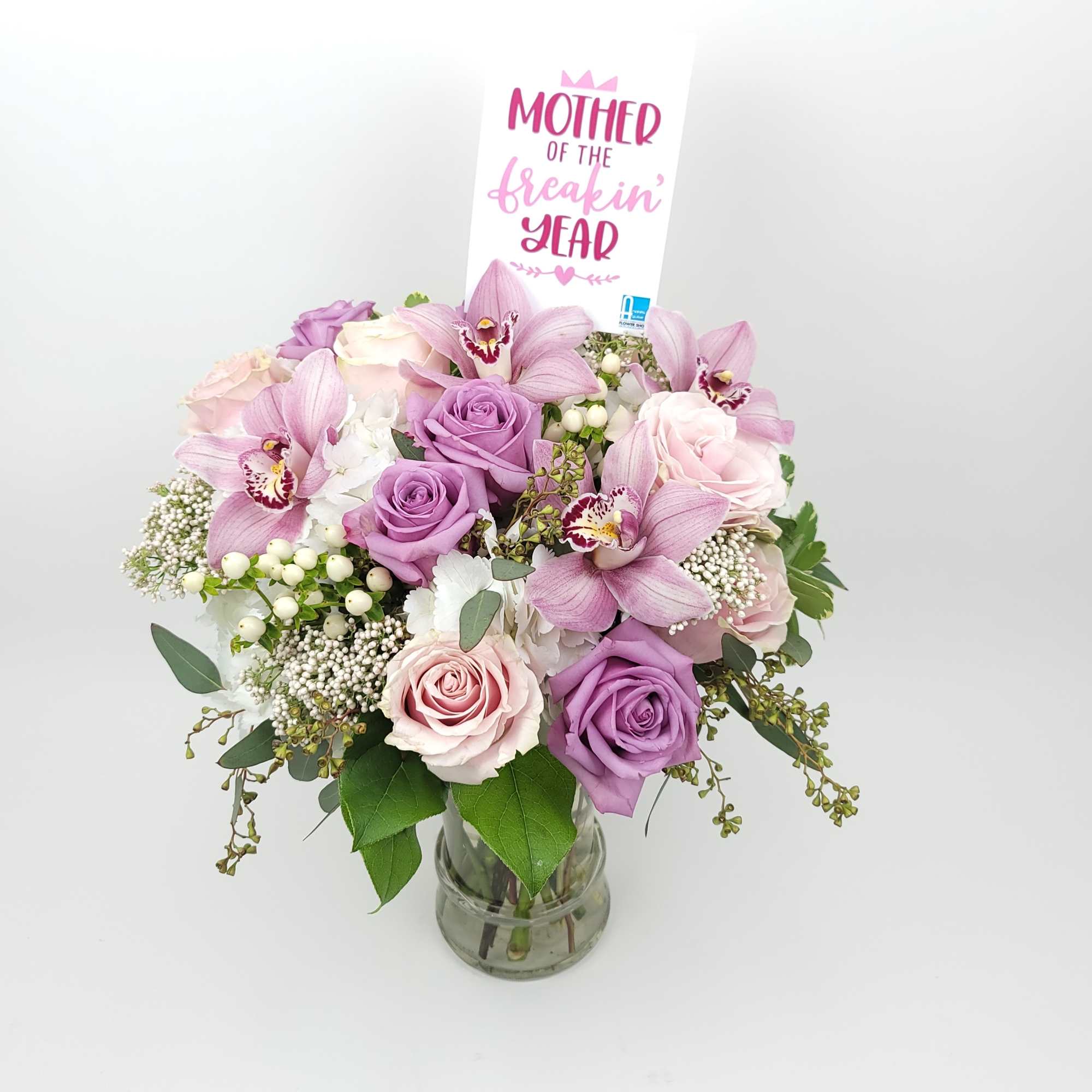 In a clear vase an arrangement with roses, hydrangeas,  cymbidium orchids