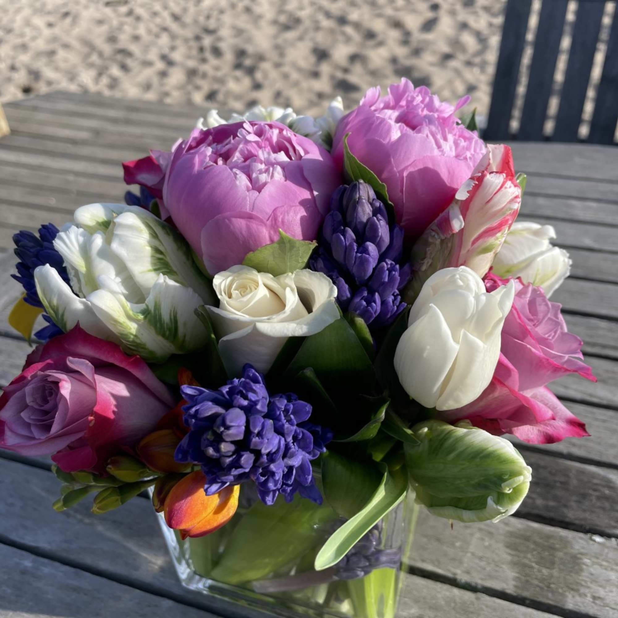 Mixed bouquet of pink, white, and purple flowers in a clear glass vase