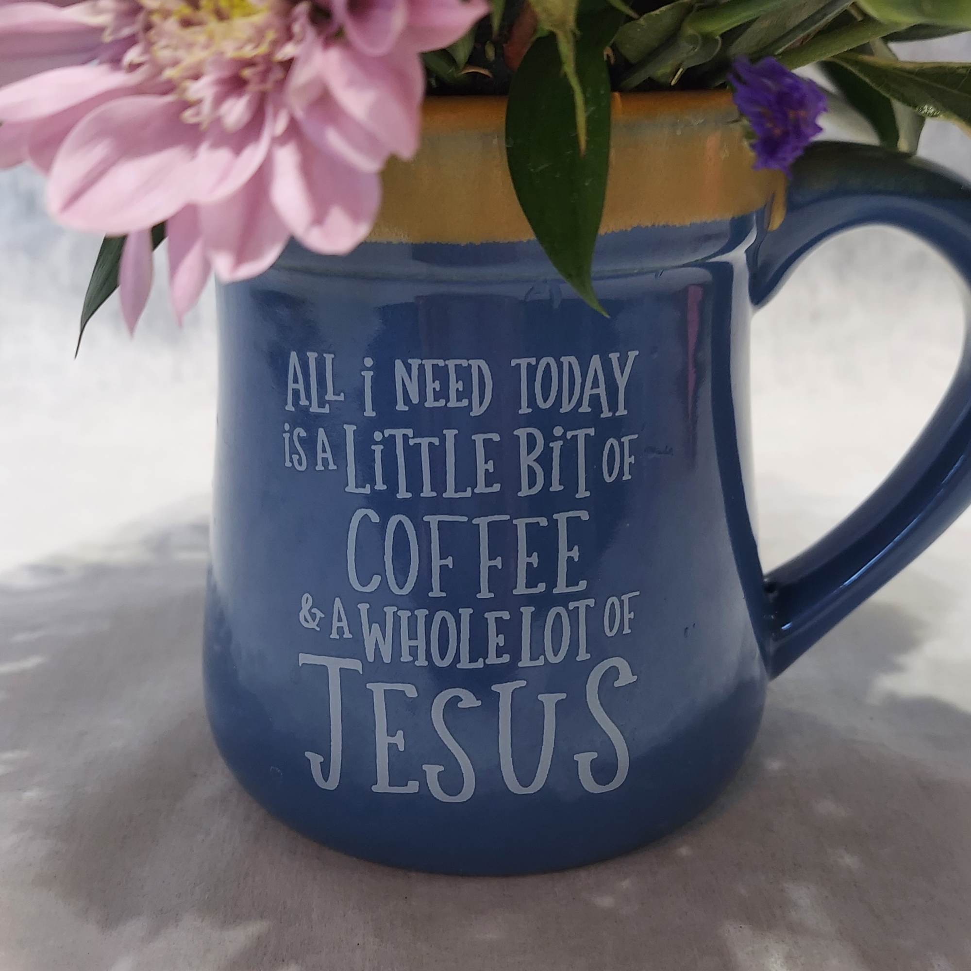 Pink flowers in a blue coffee mug with printed text